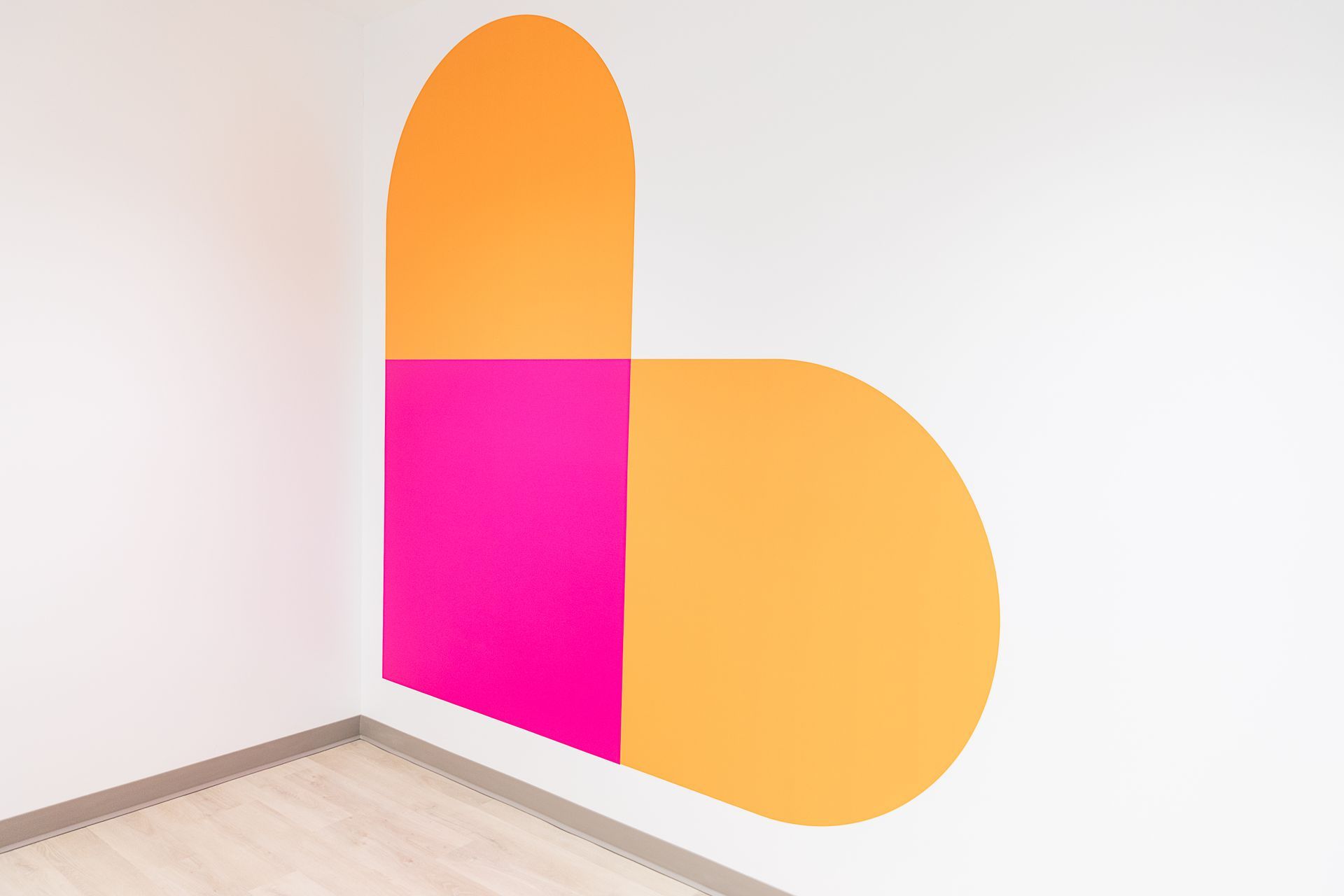 A pink and orange heart is painted on a white wall in a room.