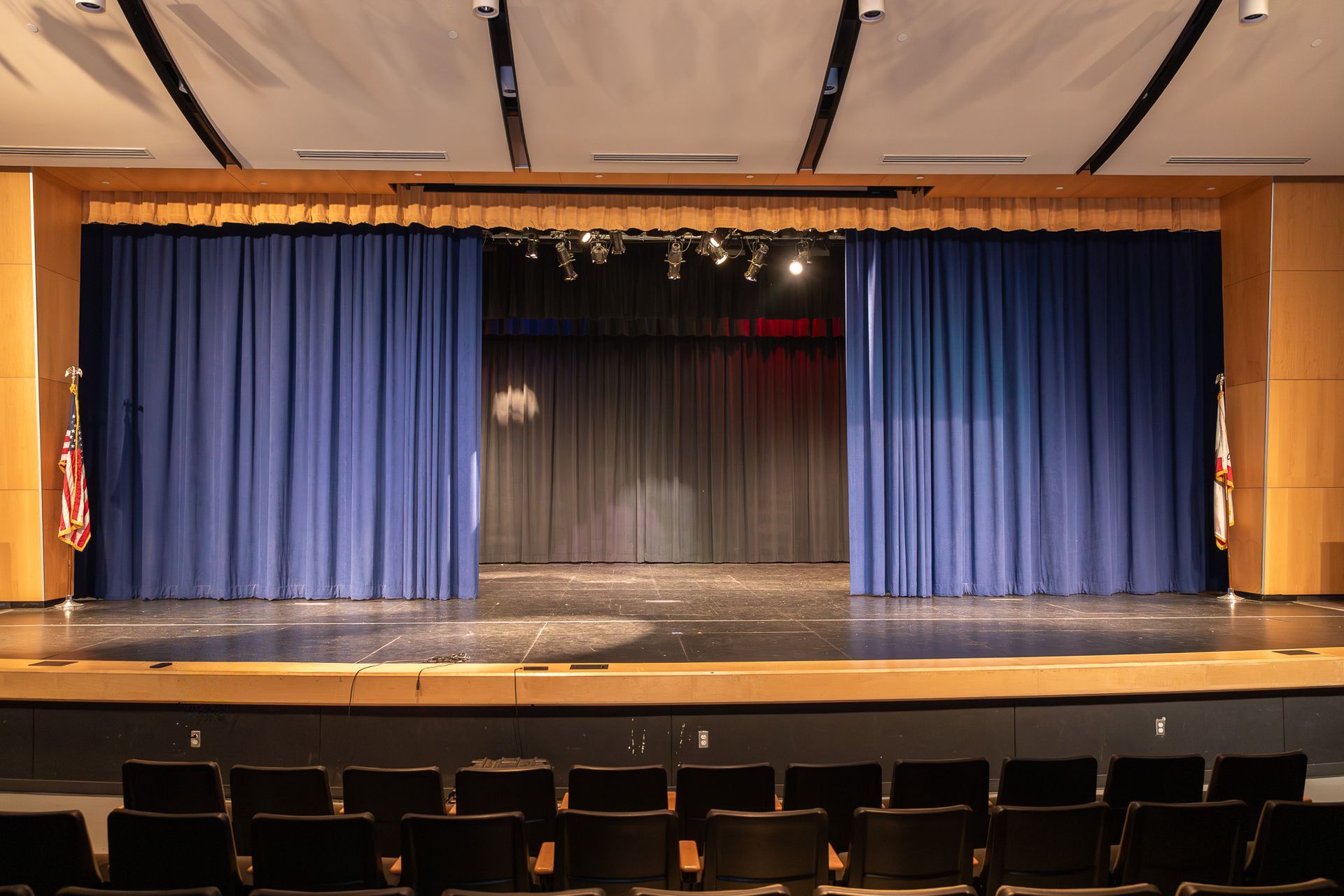 Empty theater stage with blue curtains and rows of seats in front