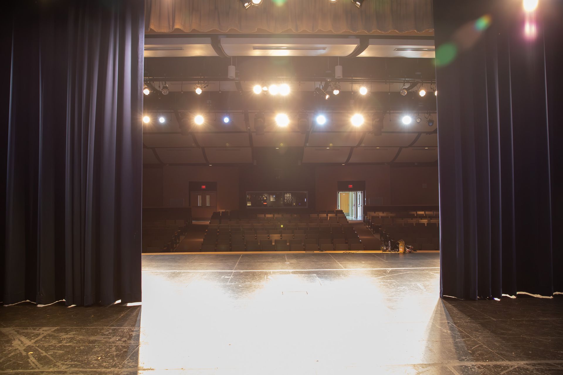 Empty theater stage with blue curtains and bright overhead lights
