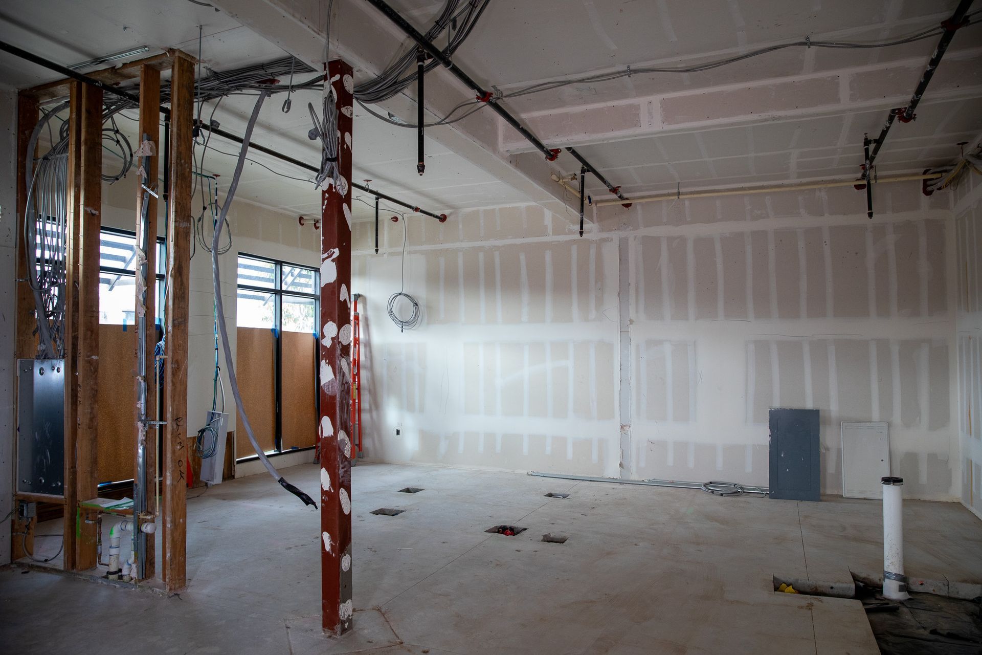 Unfinished room with exposed framing, drywall, and ceiling wiring under construction.