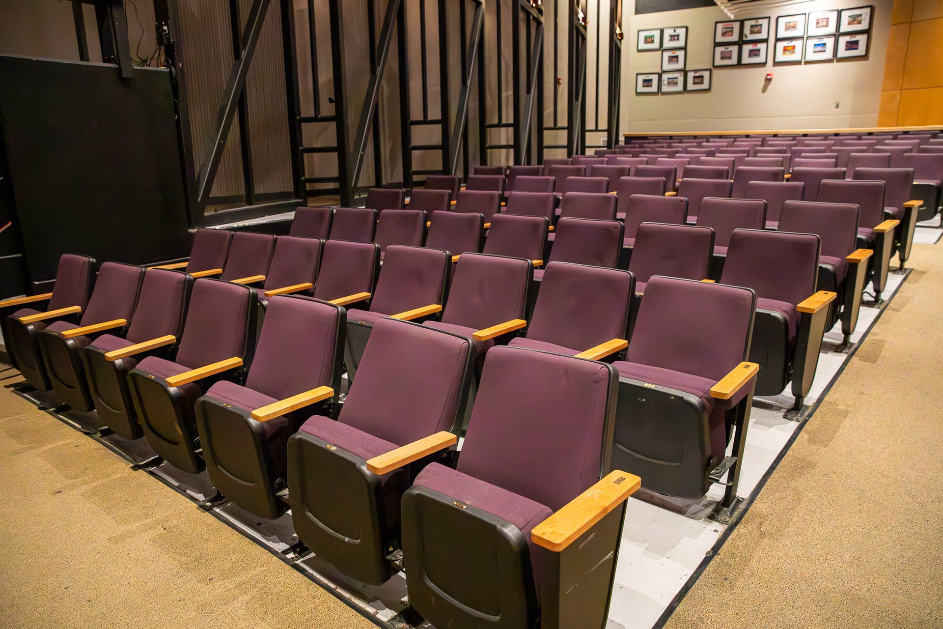 Empty auditorium with rows of purple theater seats and wooden armrests