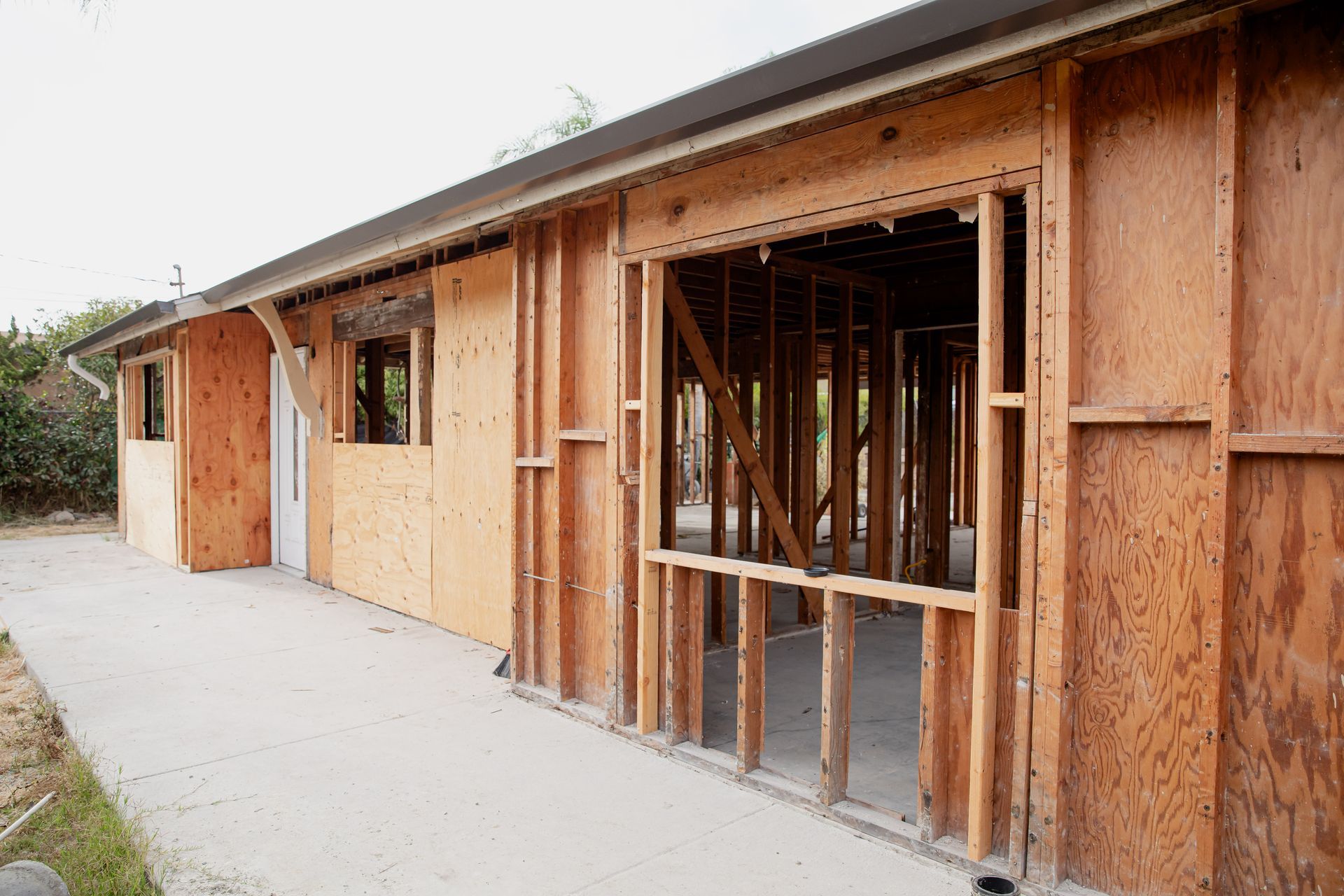Partially framed wooden house under construction with open window and door openings