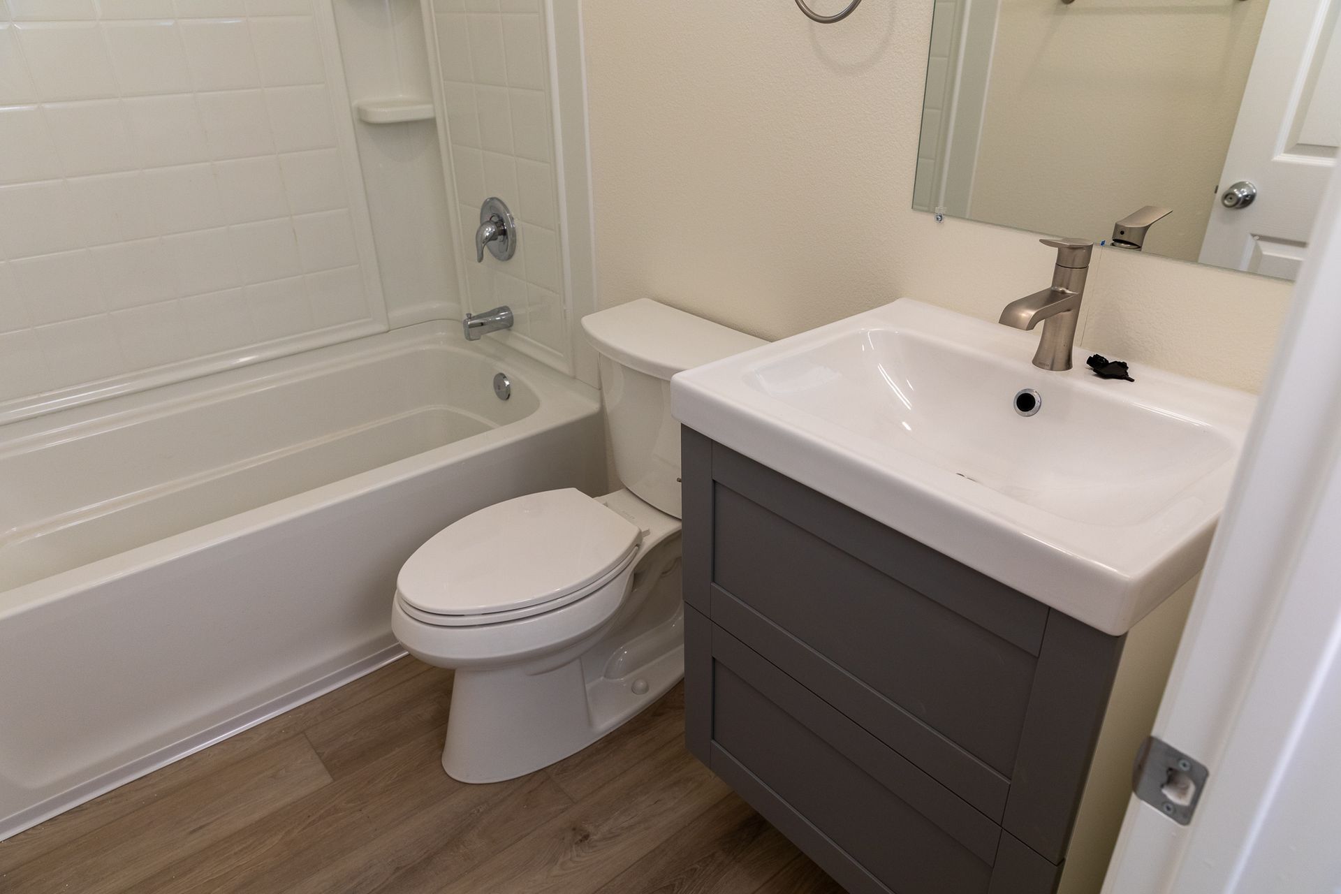 A bathroom with a toilet , sink , bathtub and mirror.
