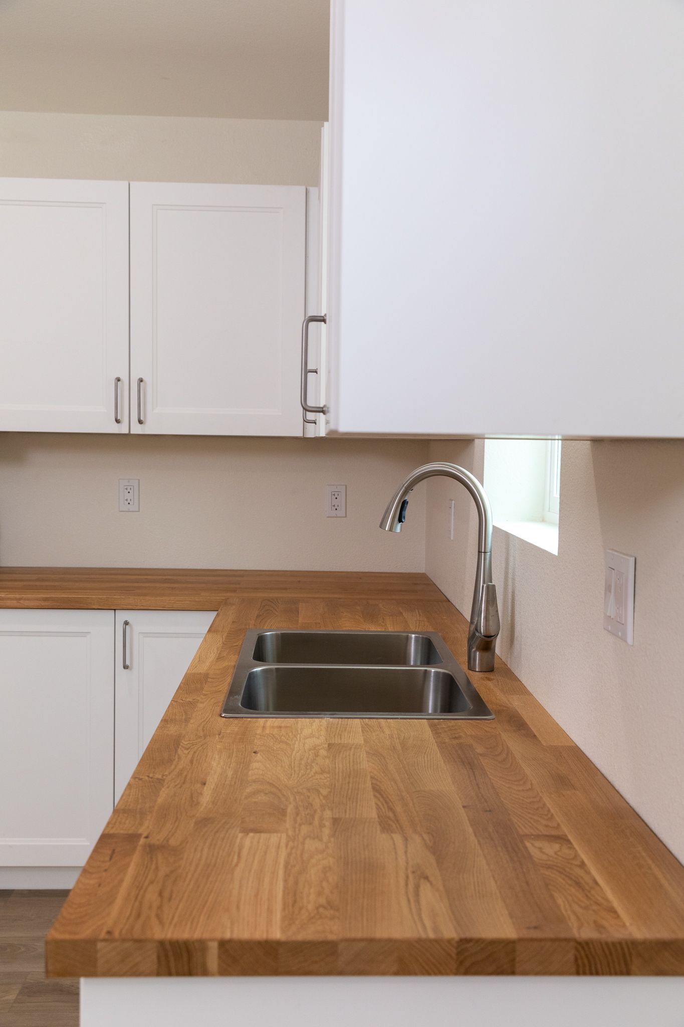A kitchen with a wooden counter top and a stainless steel sink