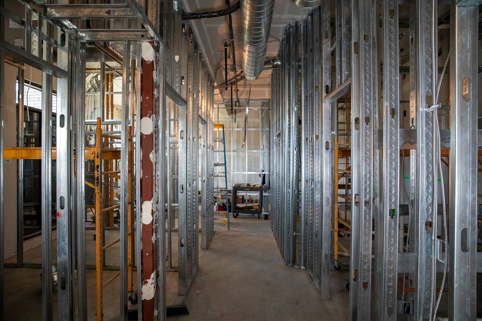 Unfinished building interior with metal wall framing, exposed ducts, and a concrete floor under construction