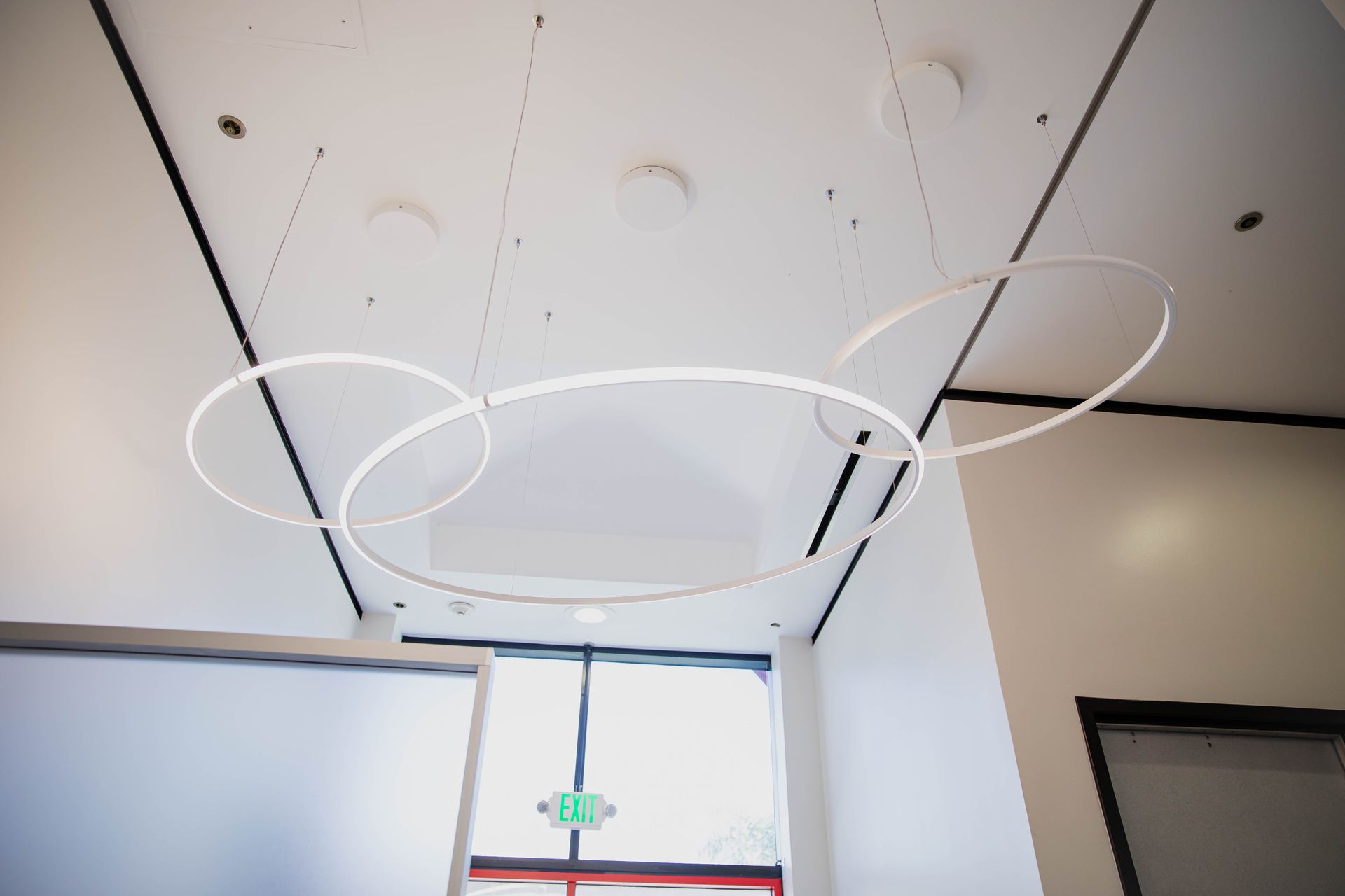 Ceiling with three large white ring-shaped lights above a doorway in a modern interior