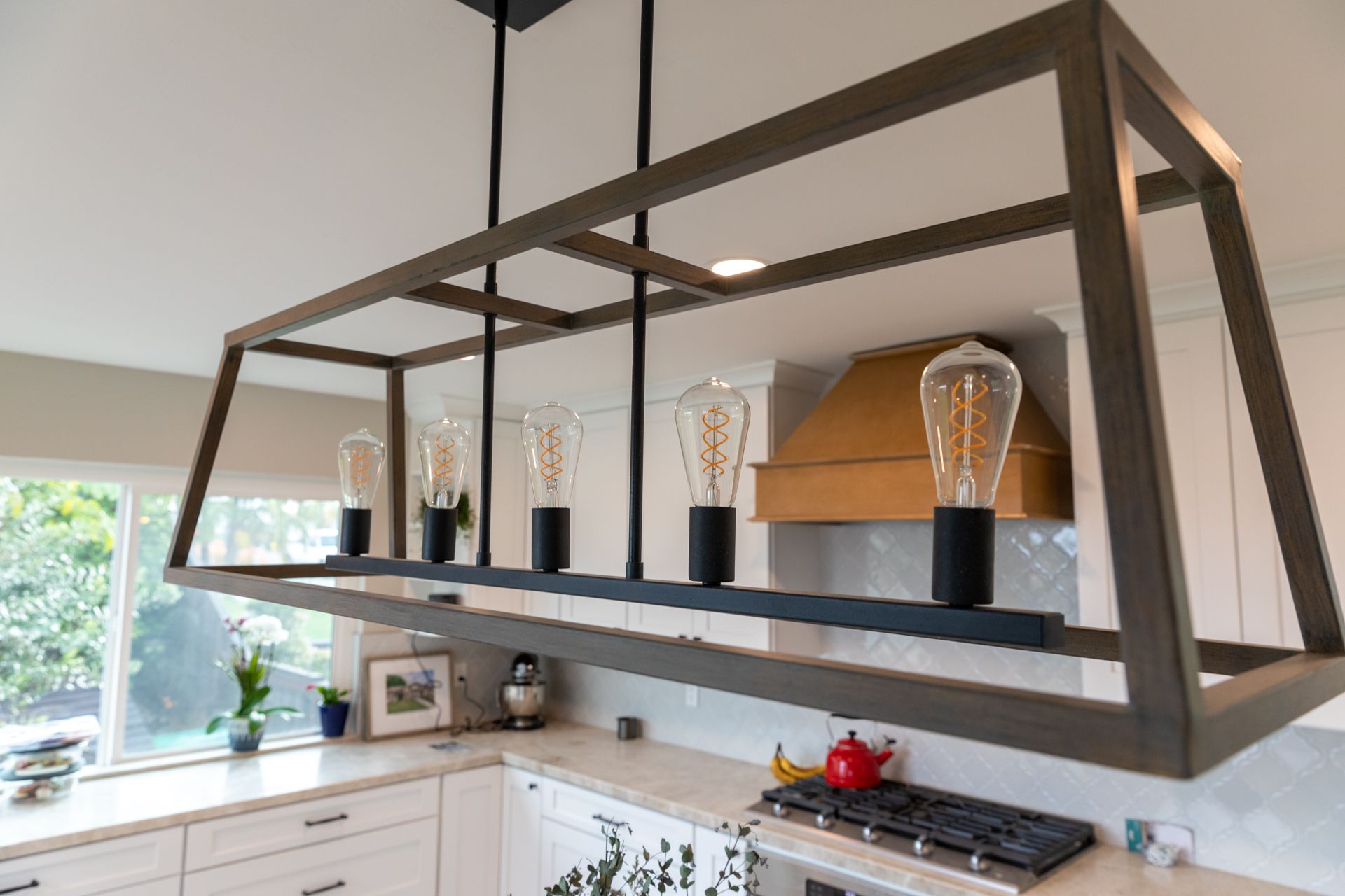 A kitchen with a stove and a chandelier hanging from the ceiling.