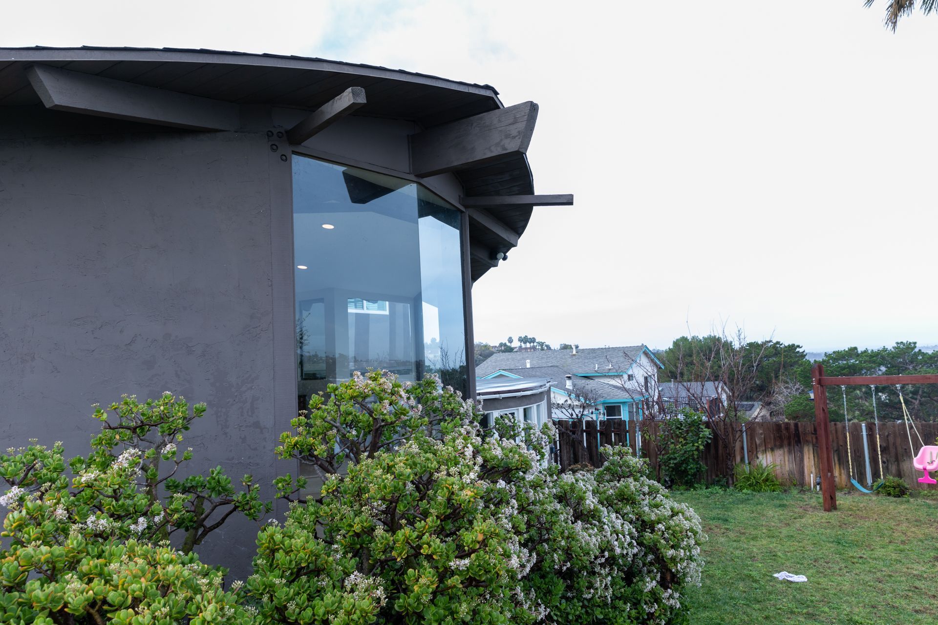 A house with a lot of windows is surrounded by trees and bushes.