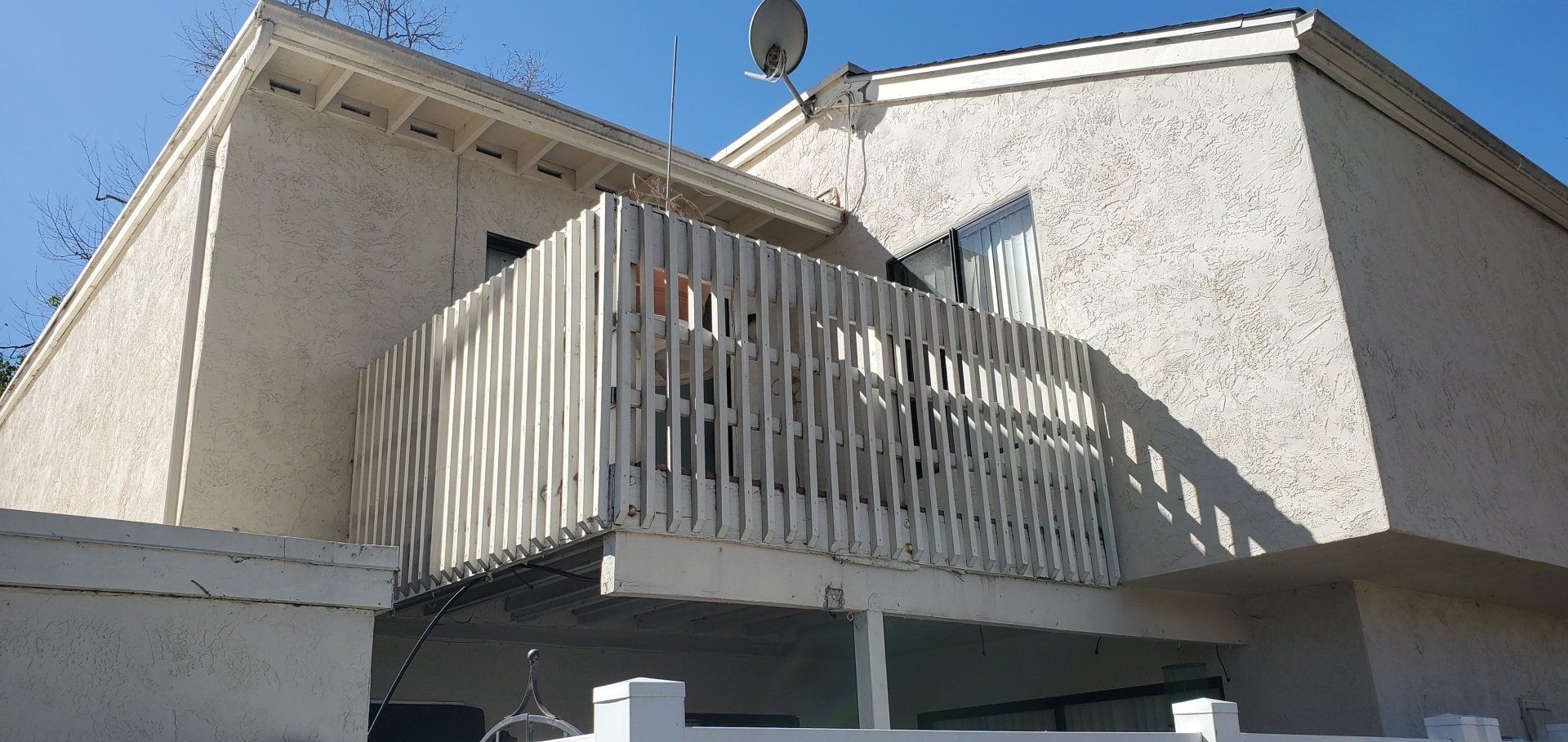 A white house with a balcony and a satellite dish on the roof