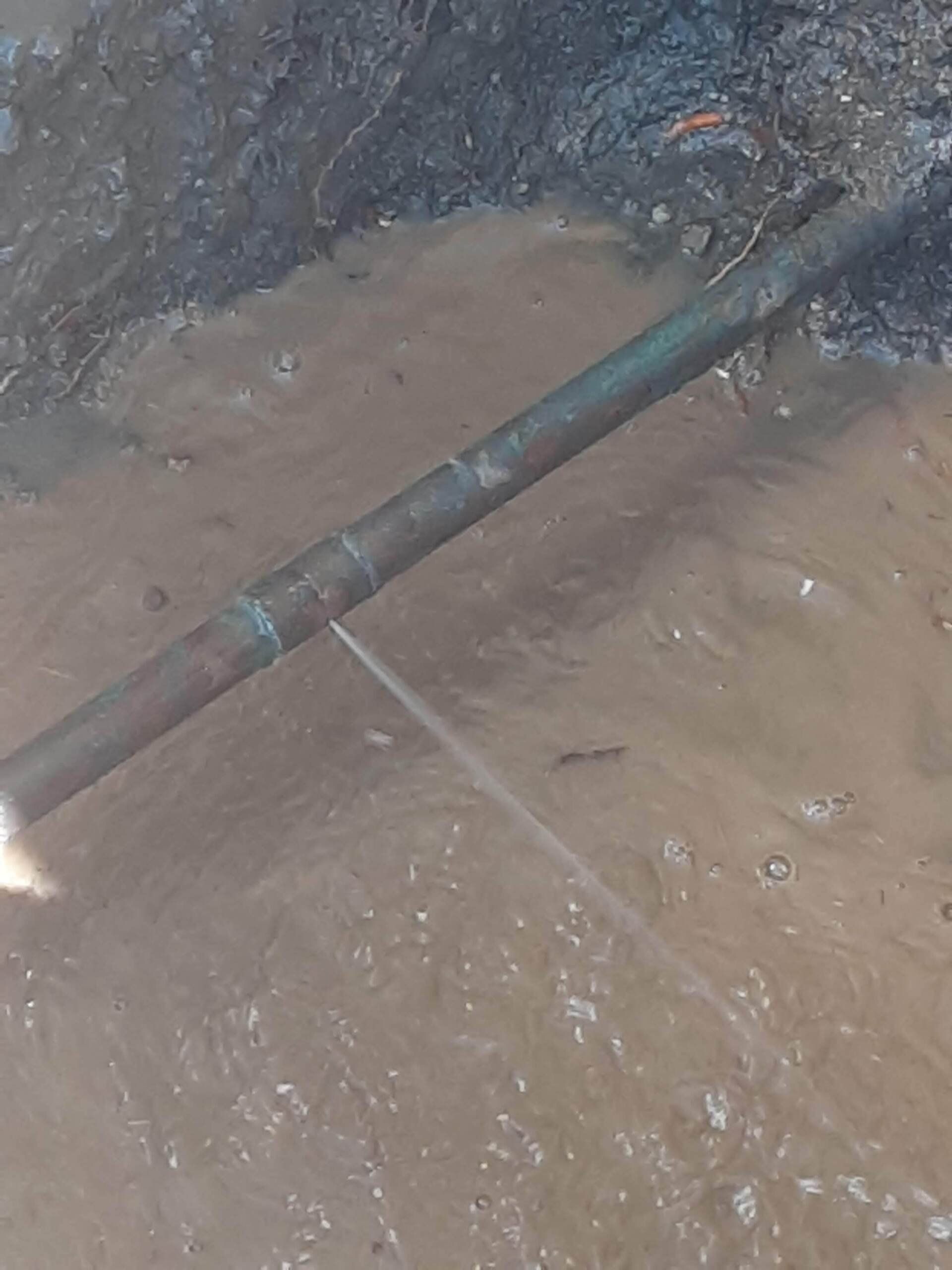 A close up of a pipe in a puddle of water.