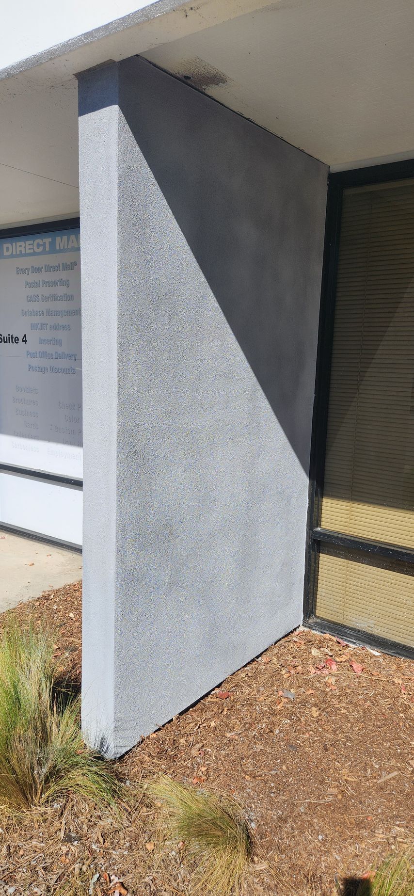 A corner of a building with a shadow on the side of it.