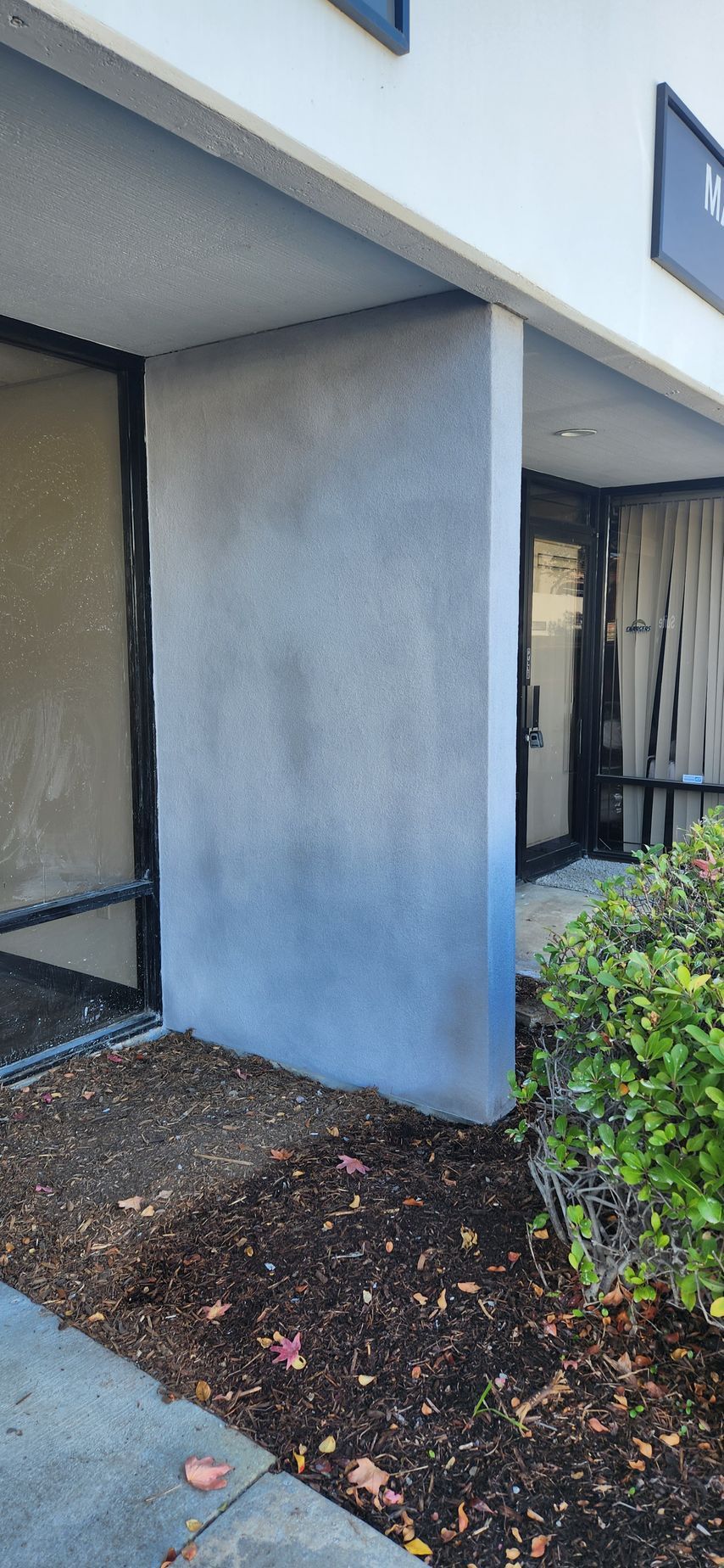 A white building with a blue pillar in front of it.