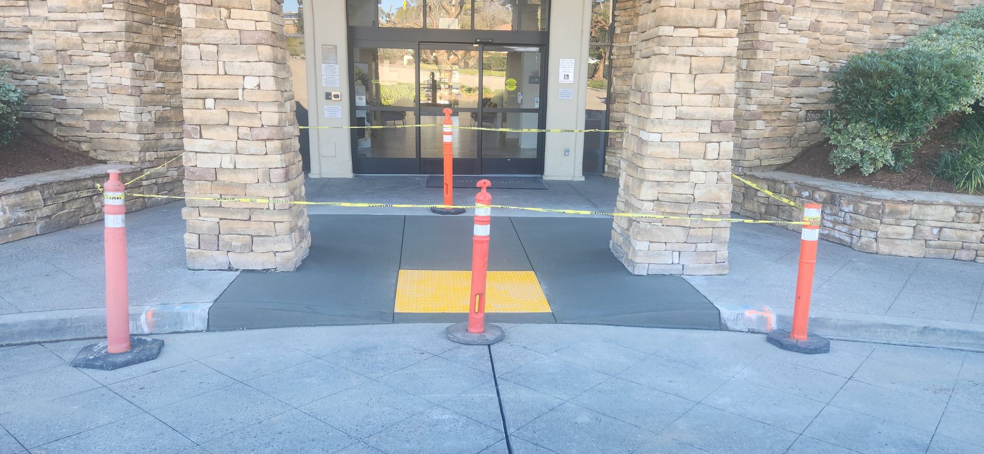 A concrete walkway with orange poles in front of a building.