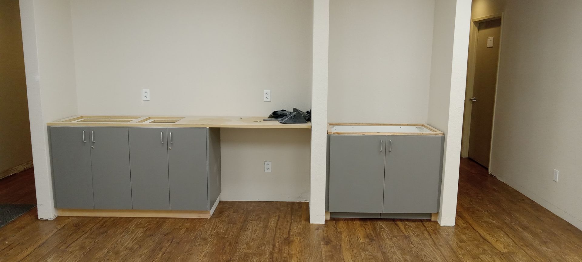 A kitchen with gray cabinets and a wooden floor.