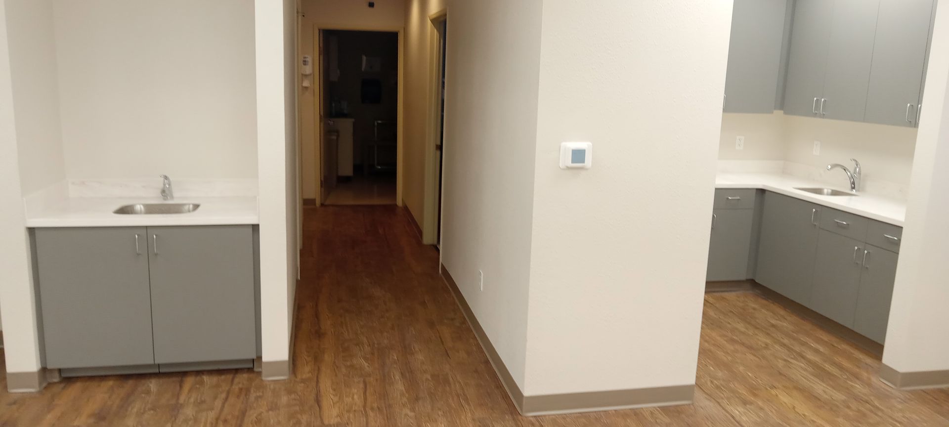 A long hallway leading to a kitchen with a sink and cabinets.