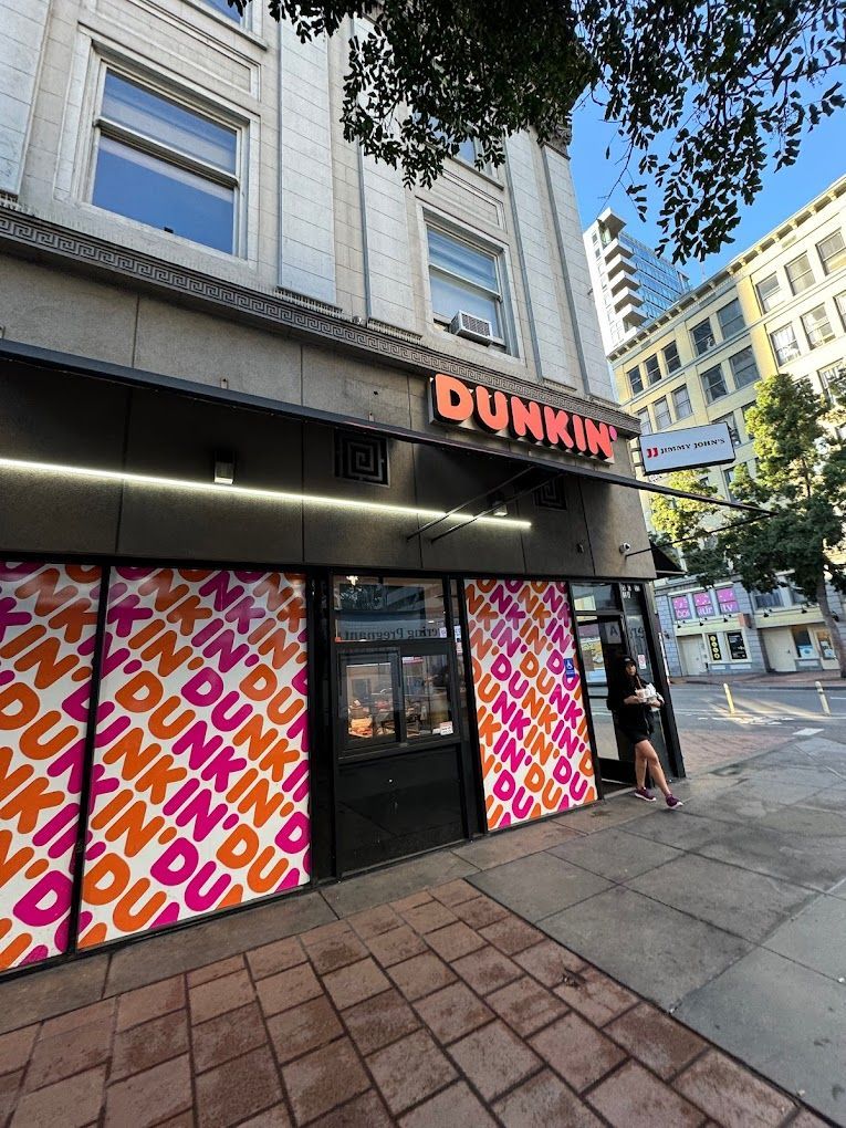 A dunkin donuts store is located on a city street.