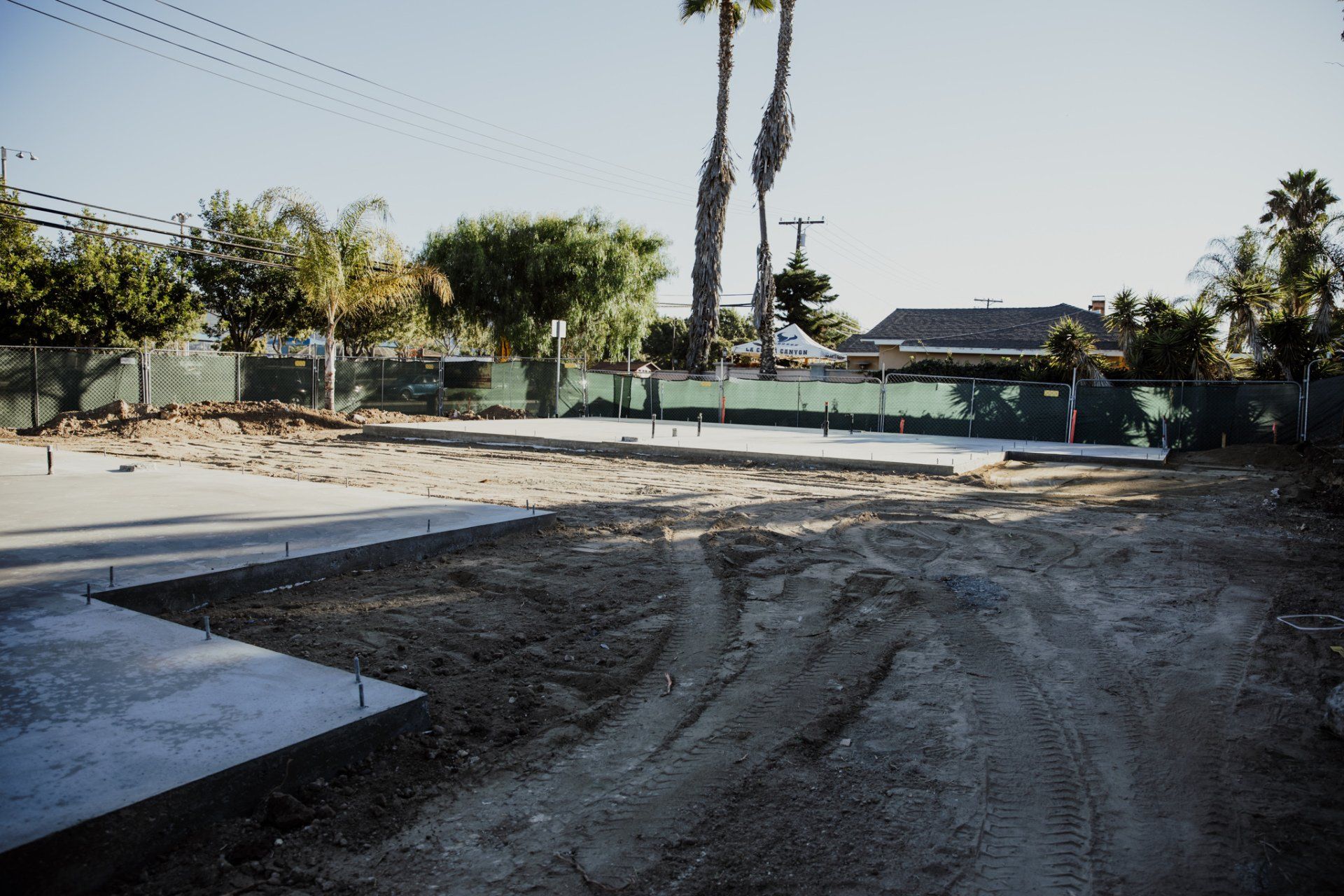A dirt road leading to a house with palm trees in the background