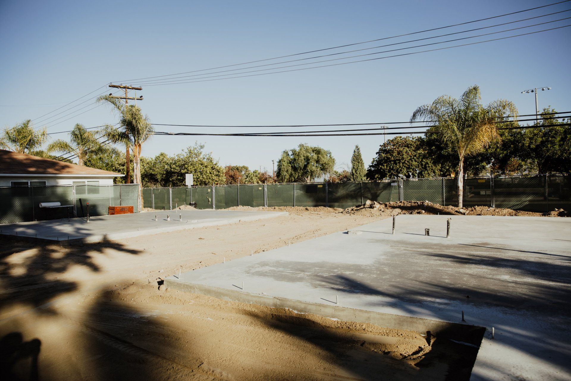 A construction site with a fence and a house in the background.