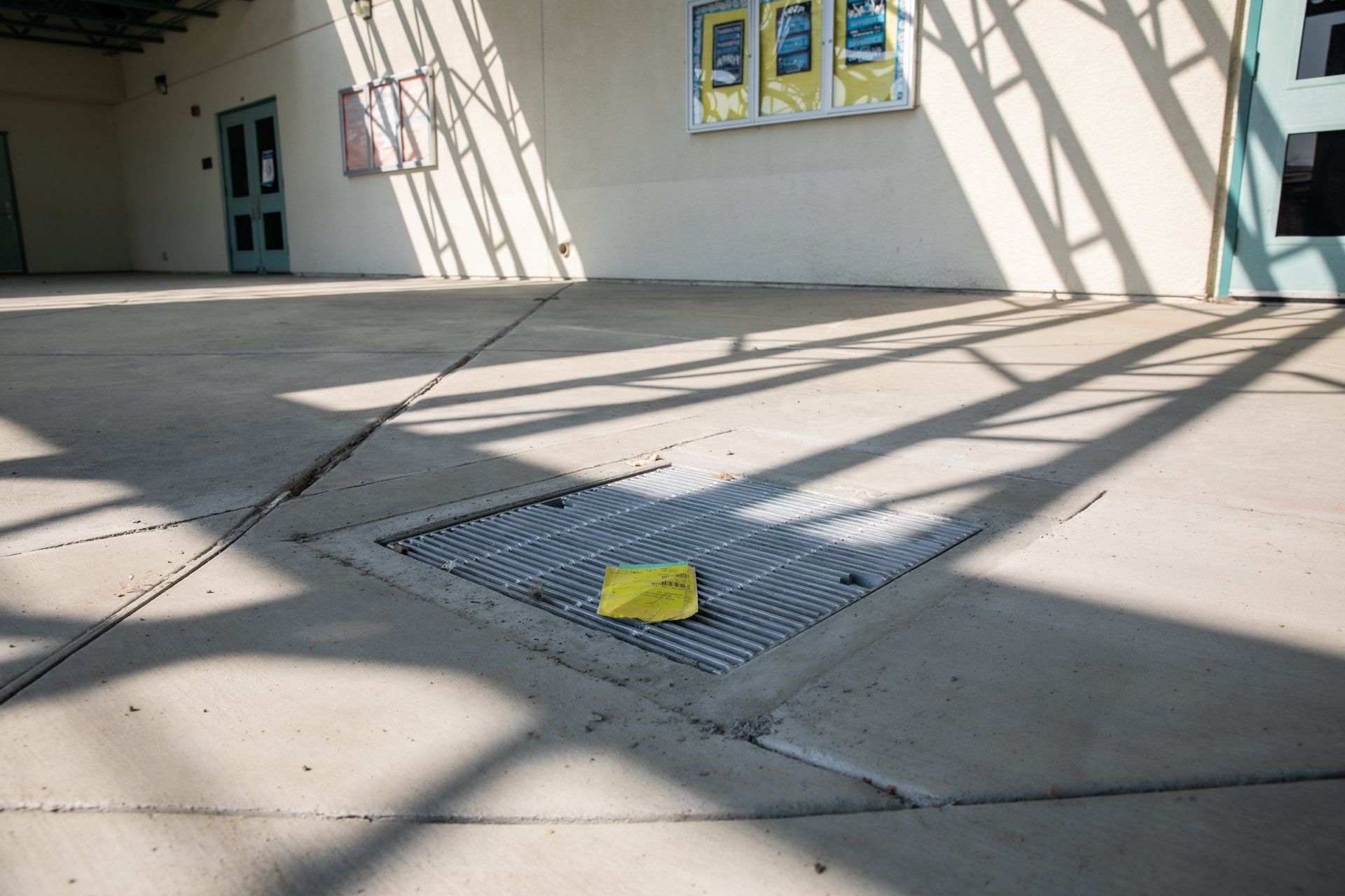 A yellow piece of paper is laying on the ground next to a manhole cover.