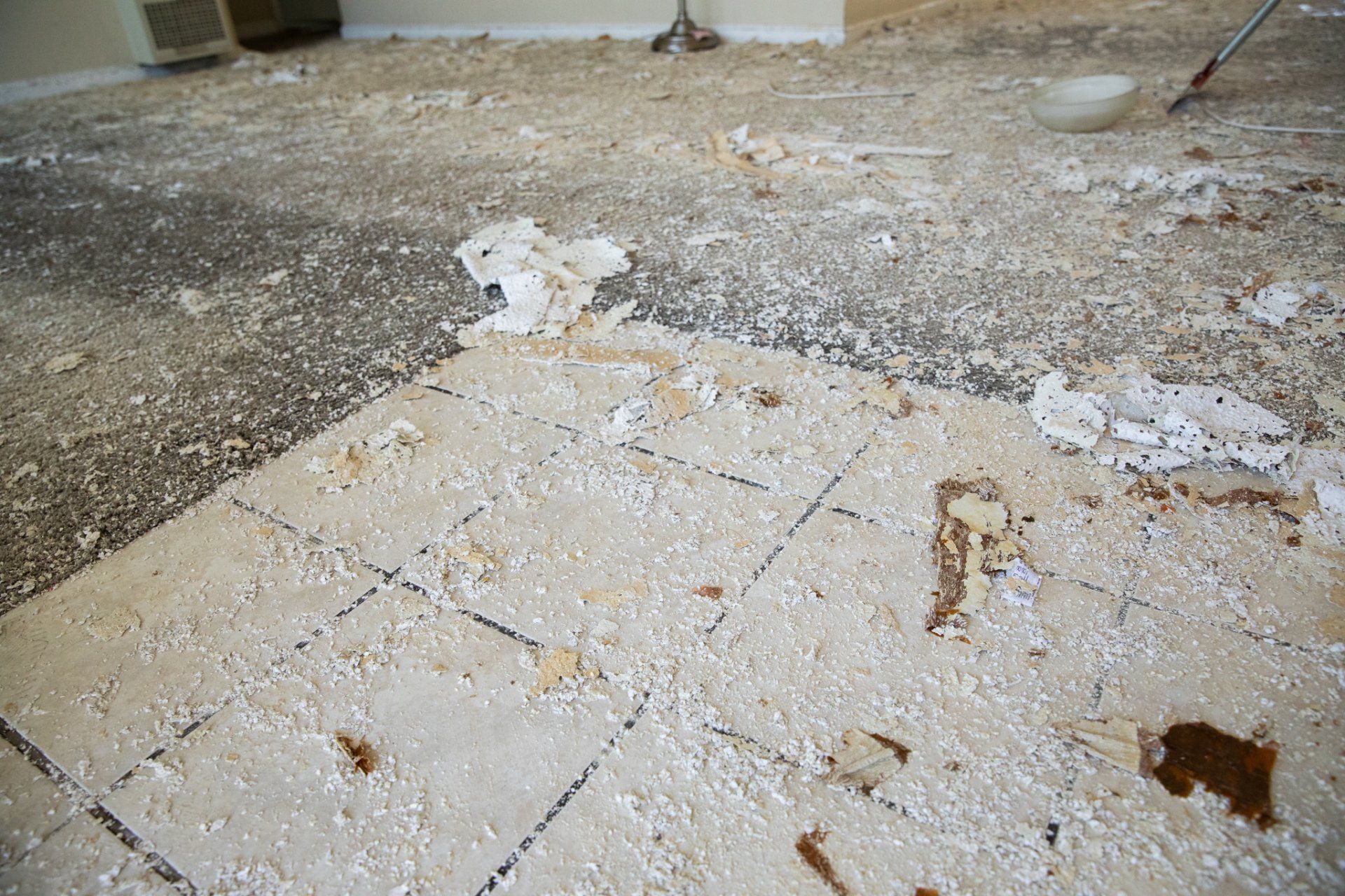 A dirty floor with a broom in the background