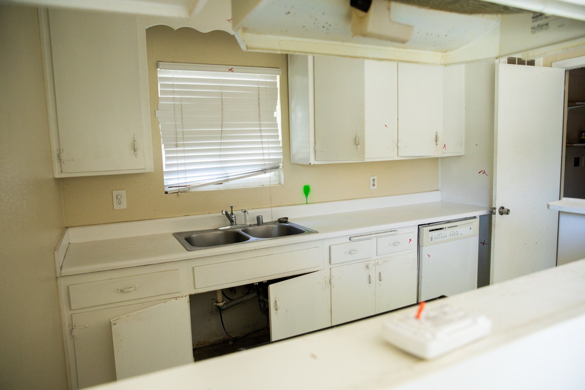 An empty kitchen with white cabinets and a sink