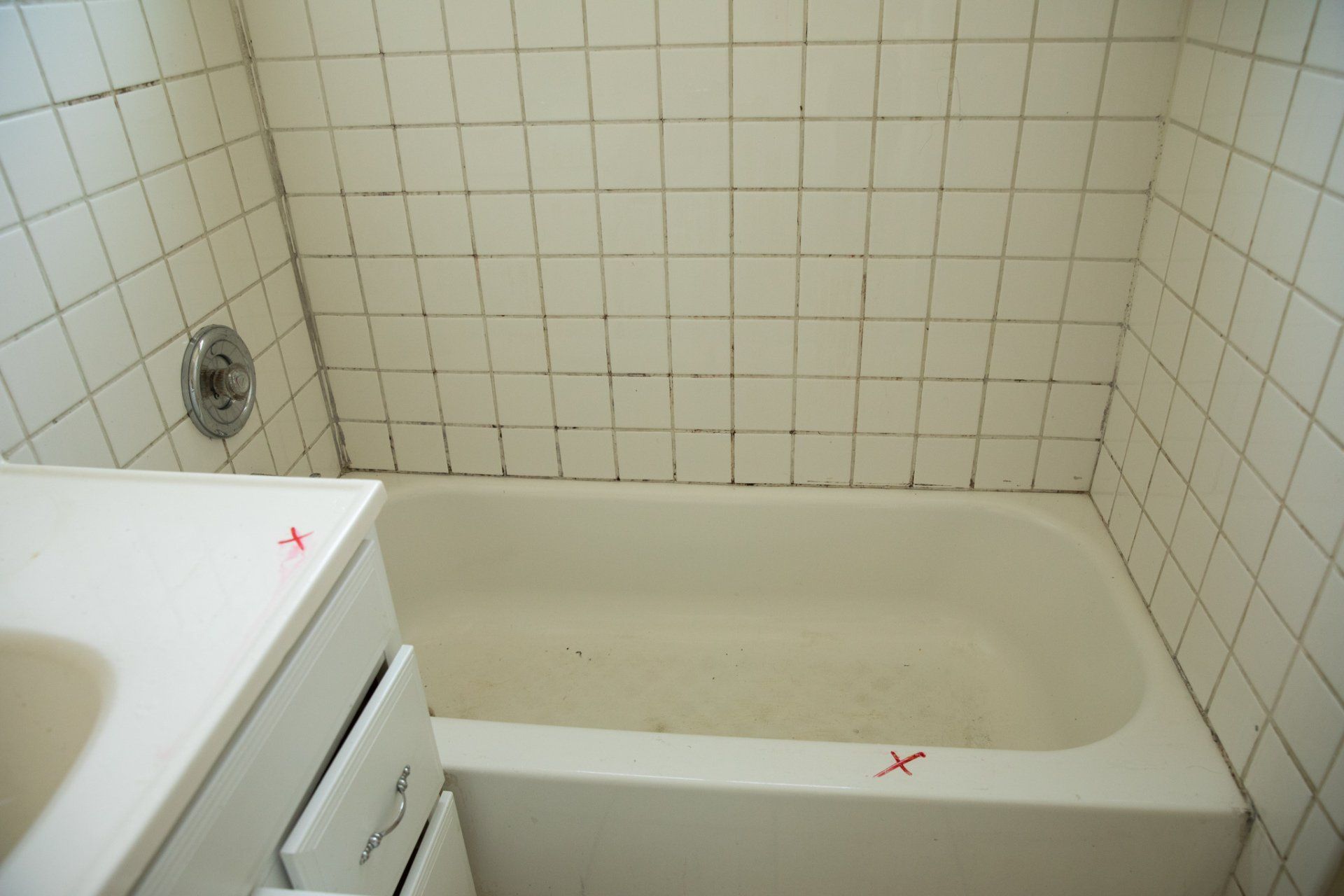 A bathroom with white tiles and a bathtub