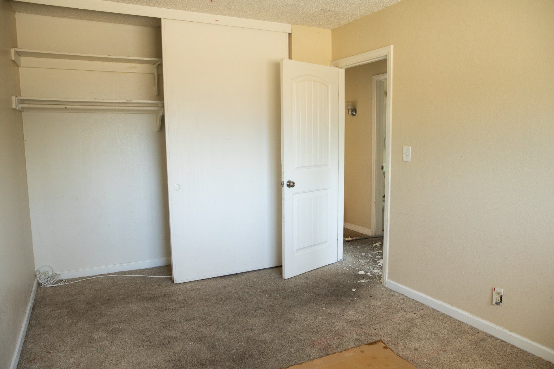 An empty bedroom with a closet and a door open
