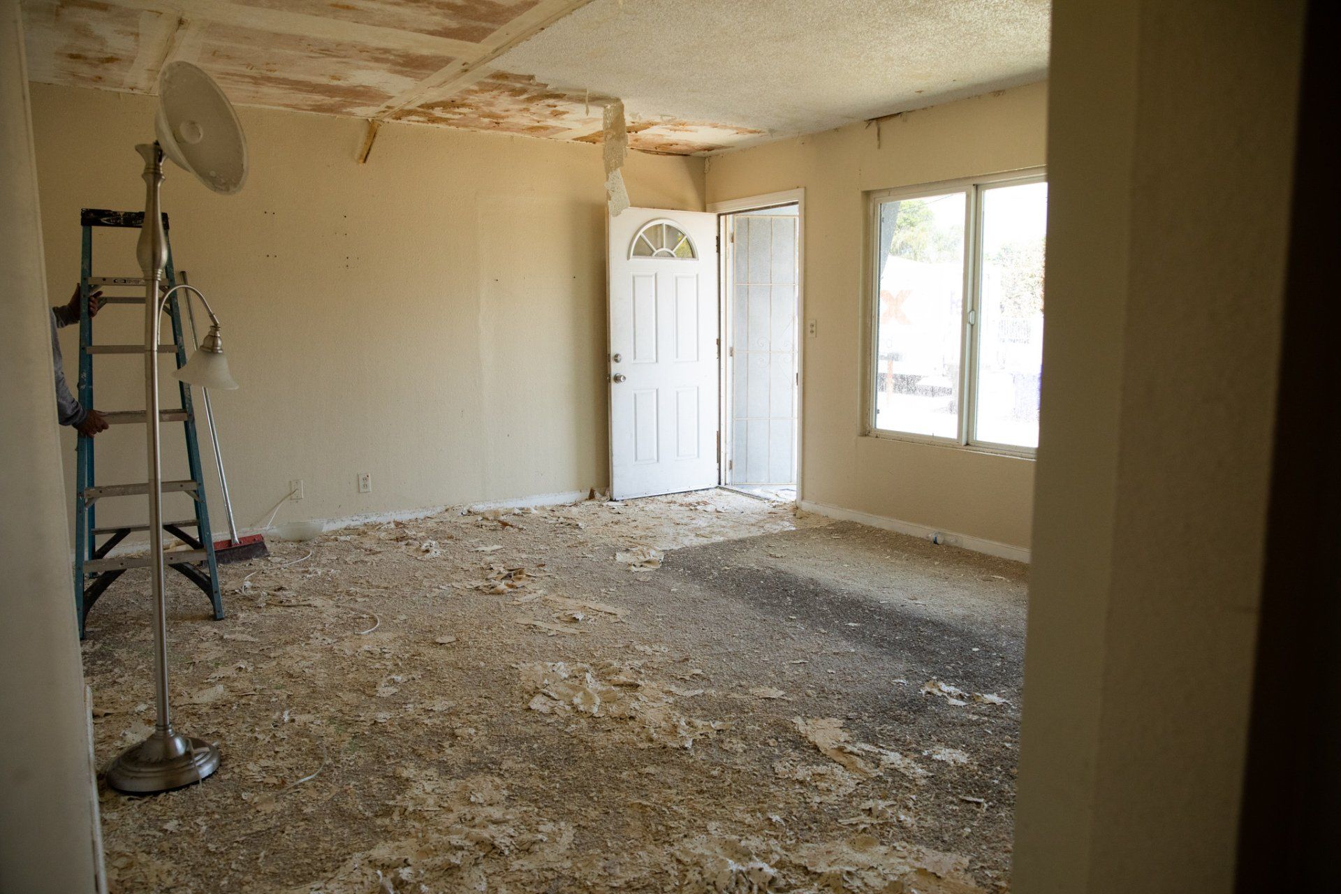 An empty room with a ladder and a fan