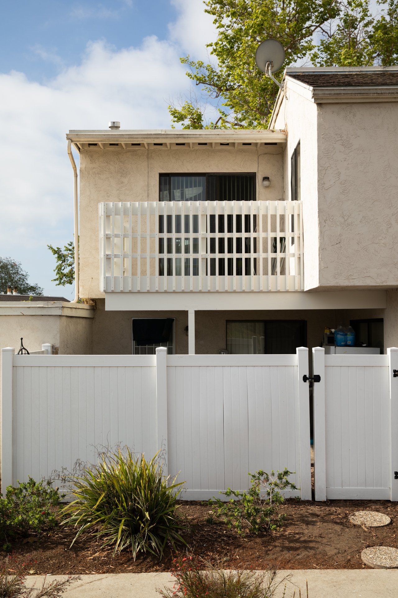 A white fence surrounds a house with a balcony