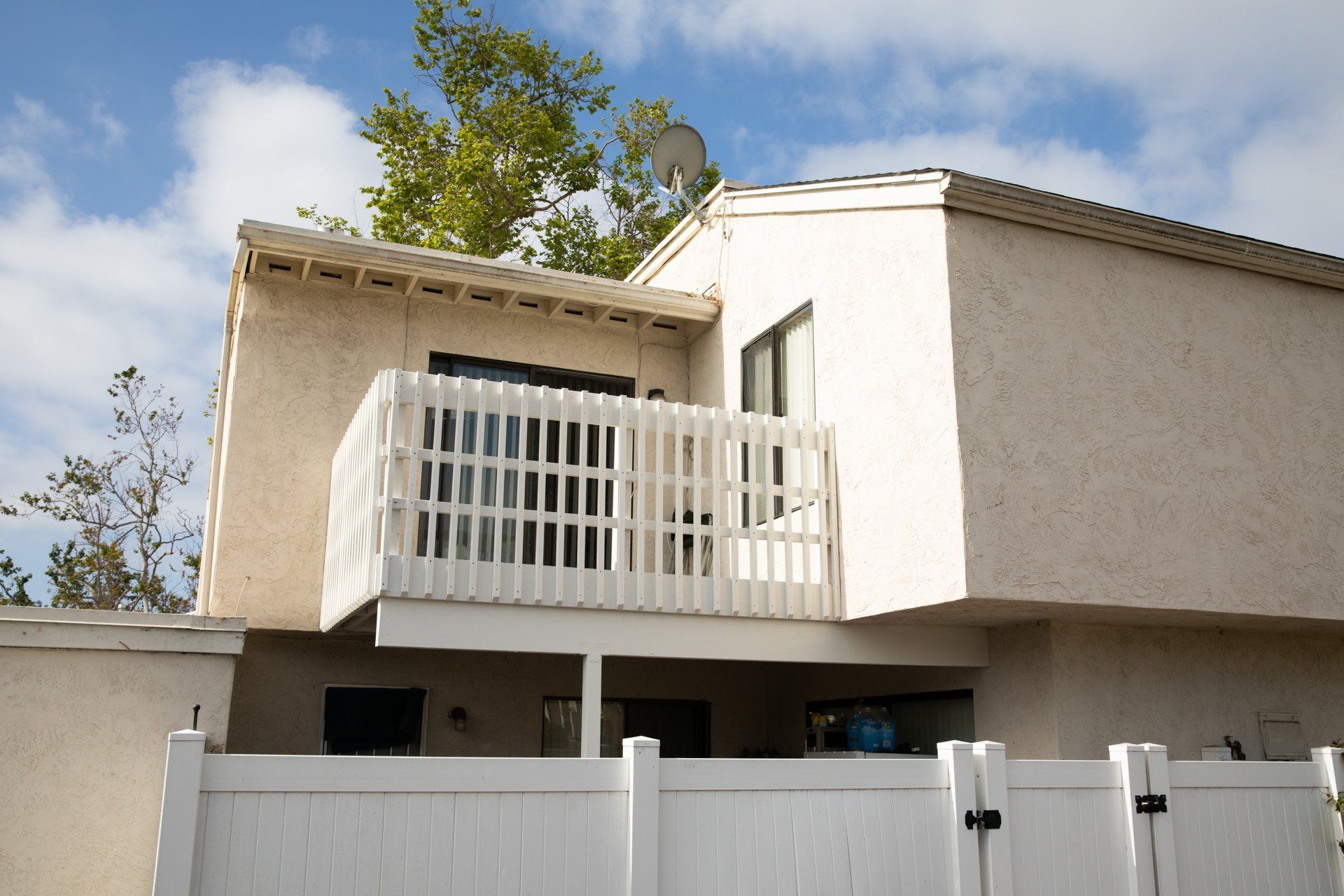 A white house with a balcony and a white fence
