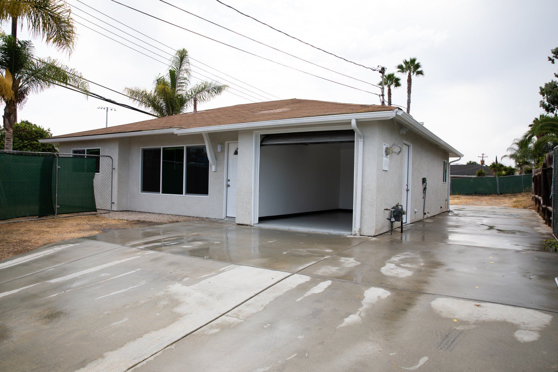 A white house with a brown roof and a concrete driveway