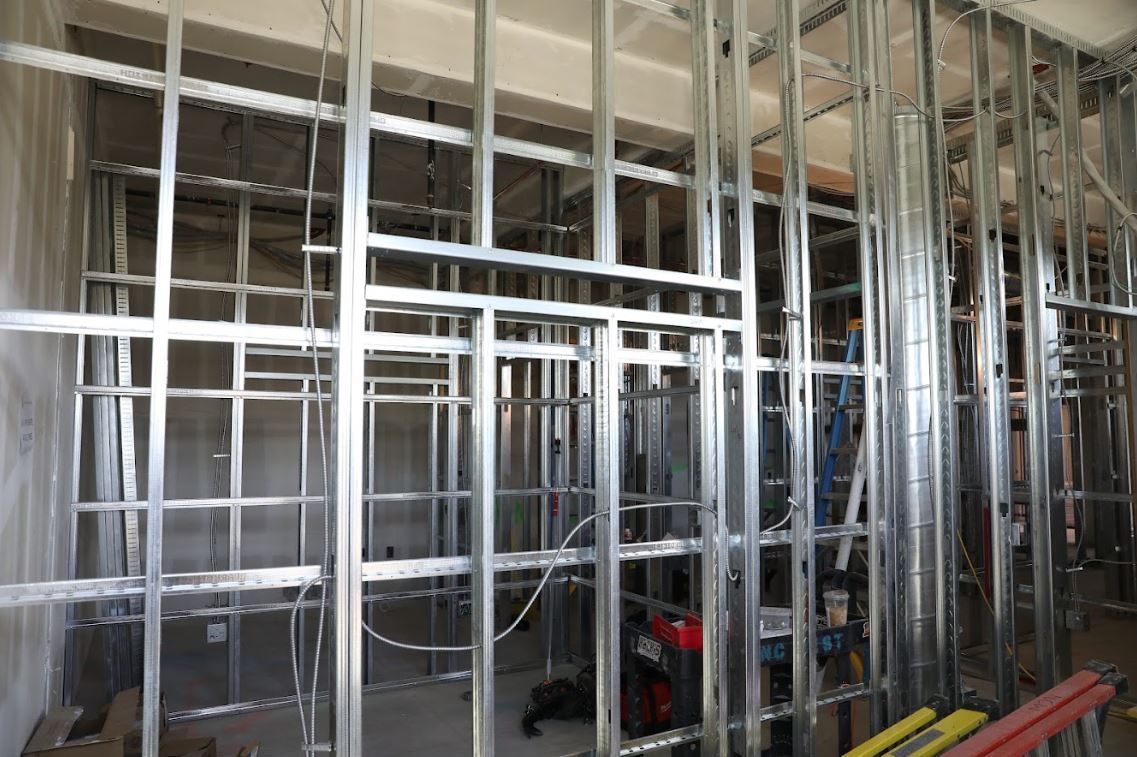 Interior construction site with metal wall framing and exposed studs in a partially finished room