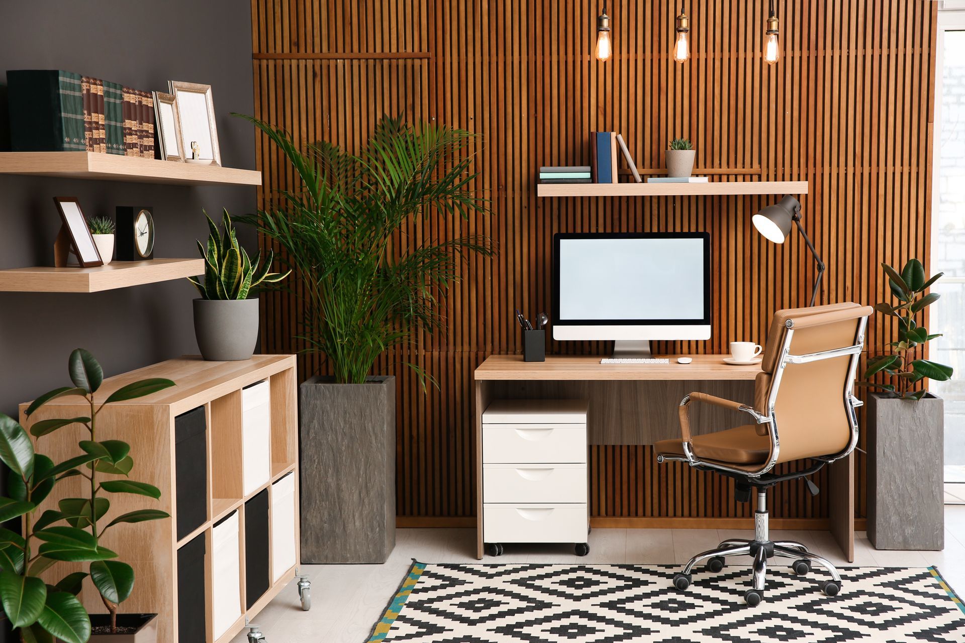 A home office with a desk , chair , computer and plants.