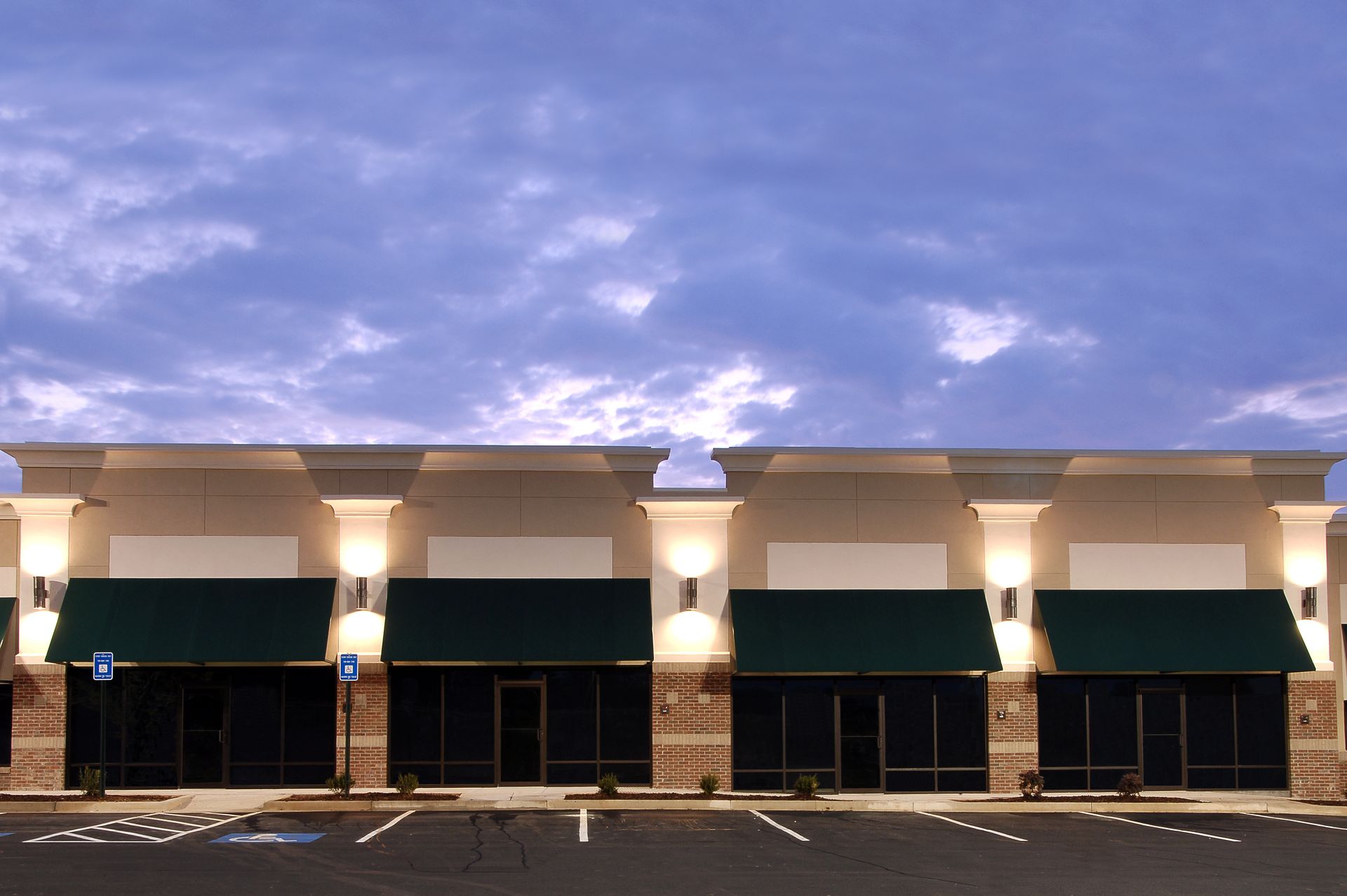 An empty parking lot in front of a building with green awnings