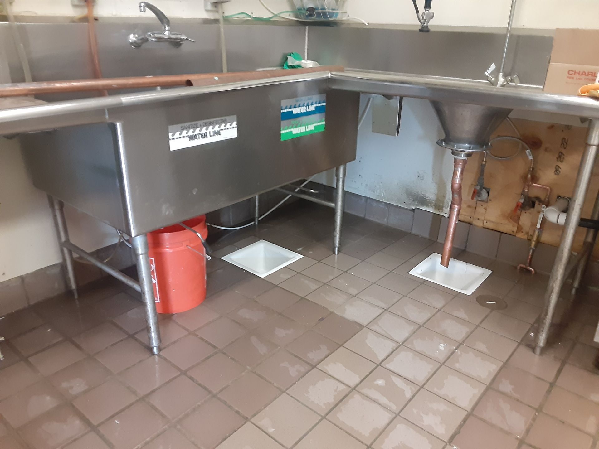 A kitchen with two sinks and a red bucket on the floor.
