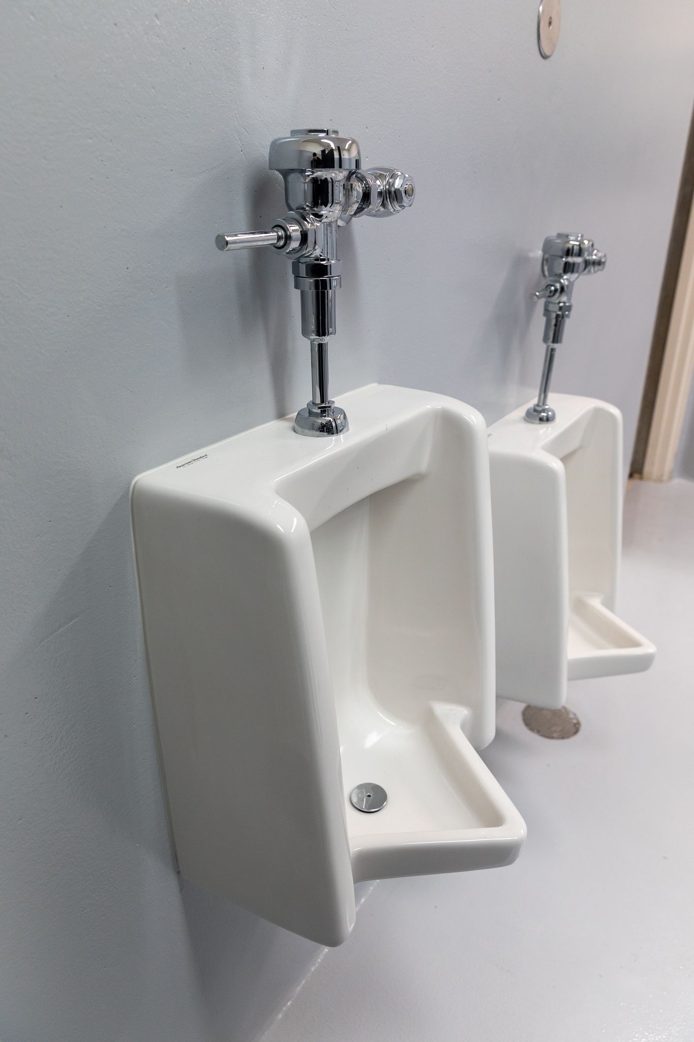 Two urinals are lined up next to each other in a bathroom.