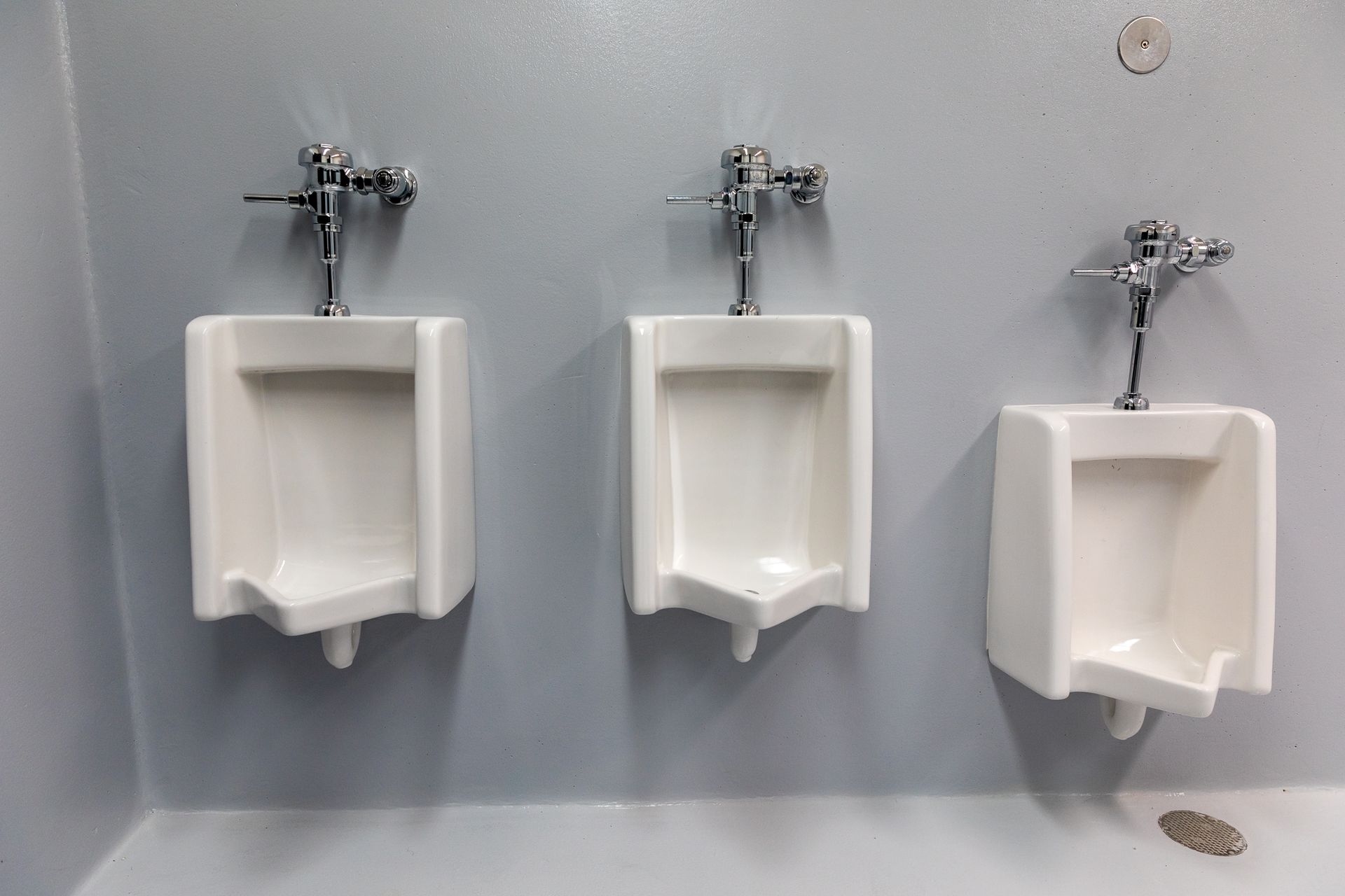 Three urinals are lined up next to each other in a bathroom.