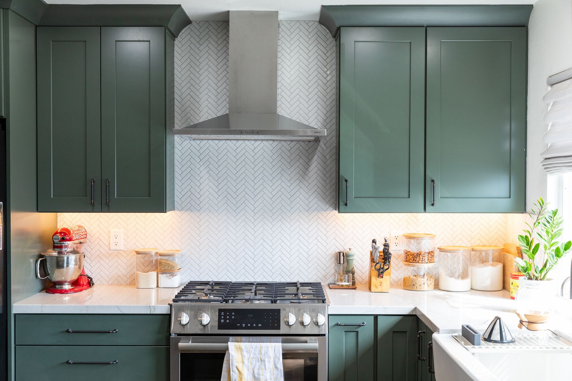 A kitchen with green cabinets and stainless steel appliances