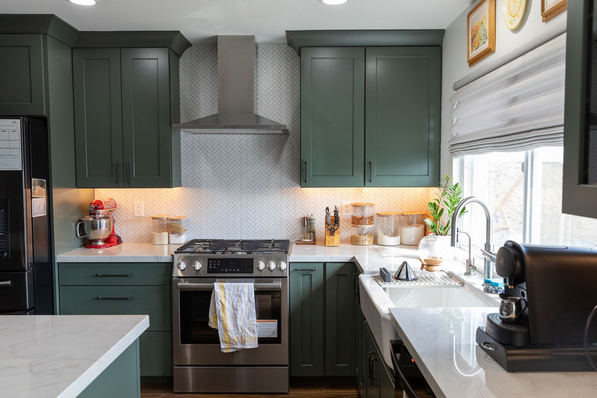 A kitchen with green cabinets and stainless steel appliances