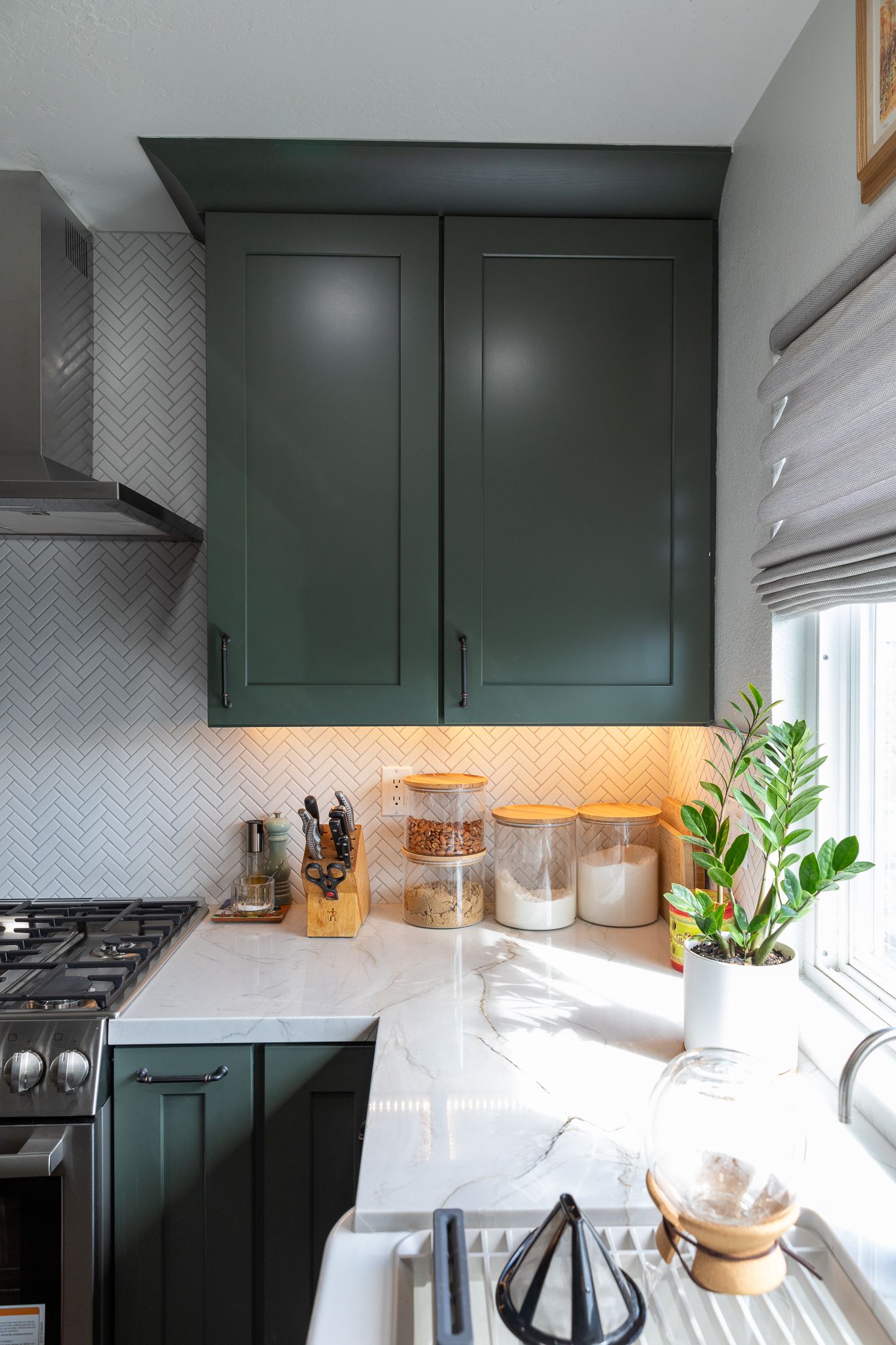 A kitchen with green cabinets and white counter tops