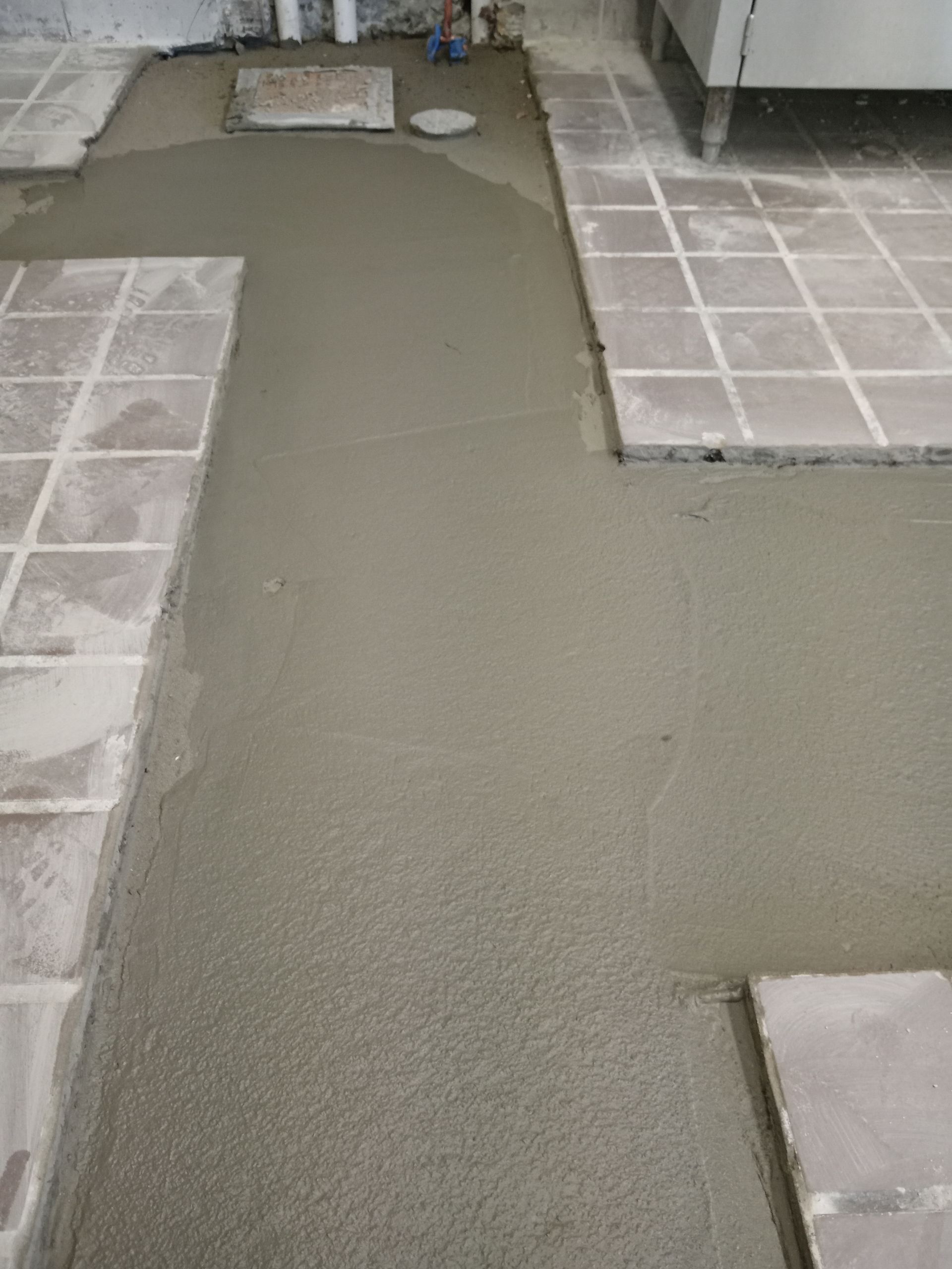 A tile floor is being installed in a bathroom.