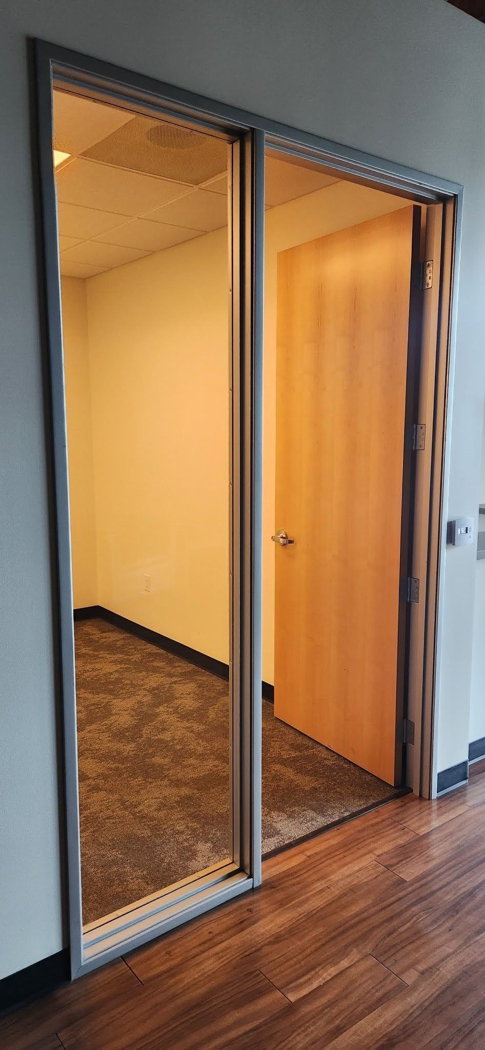 A room with a wooden door and a mirror on the wall