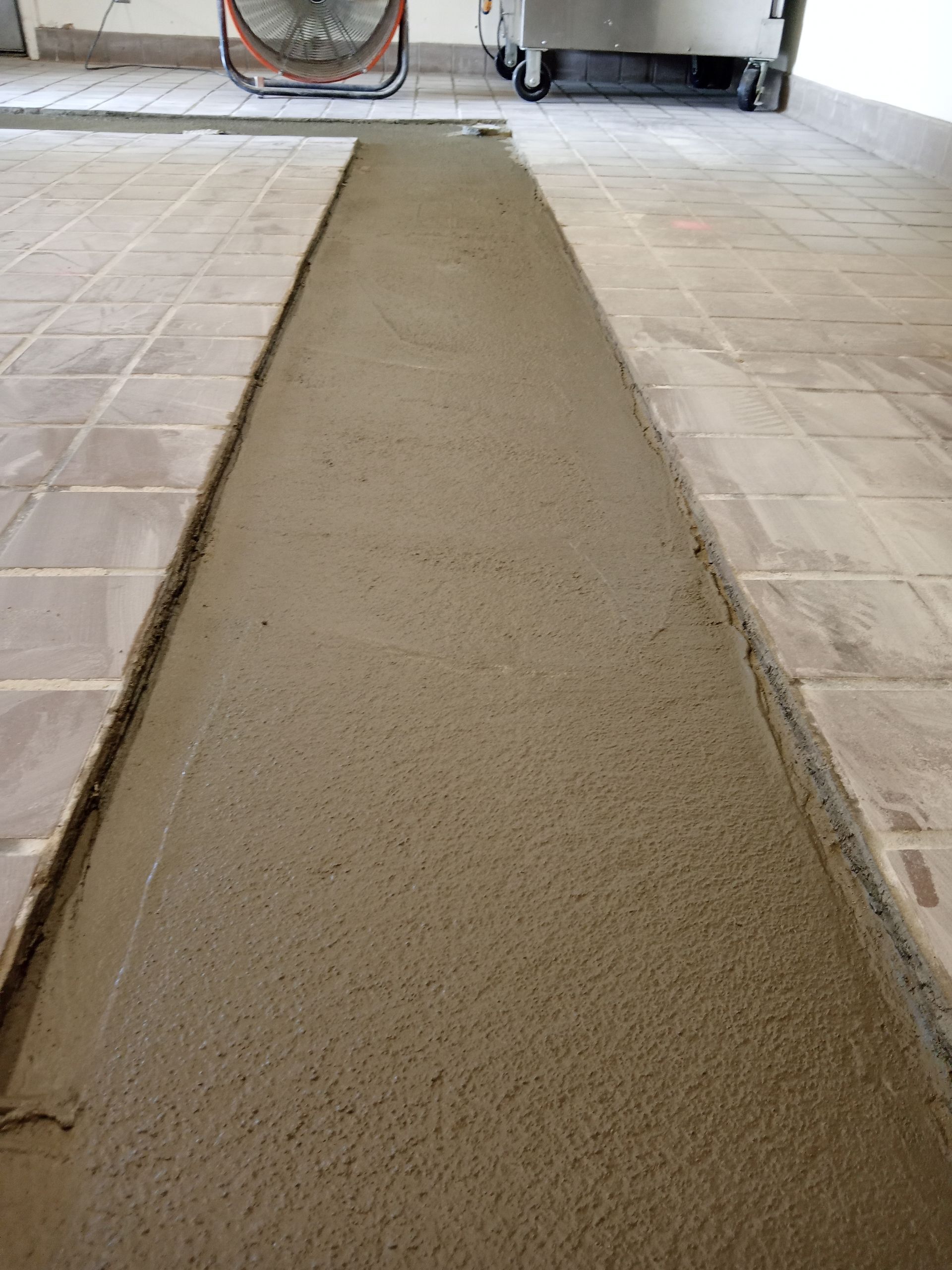A concrete floor with a fan in the background