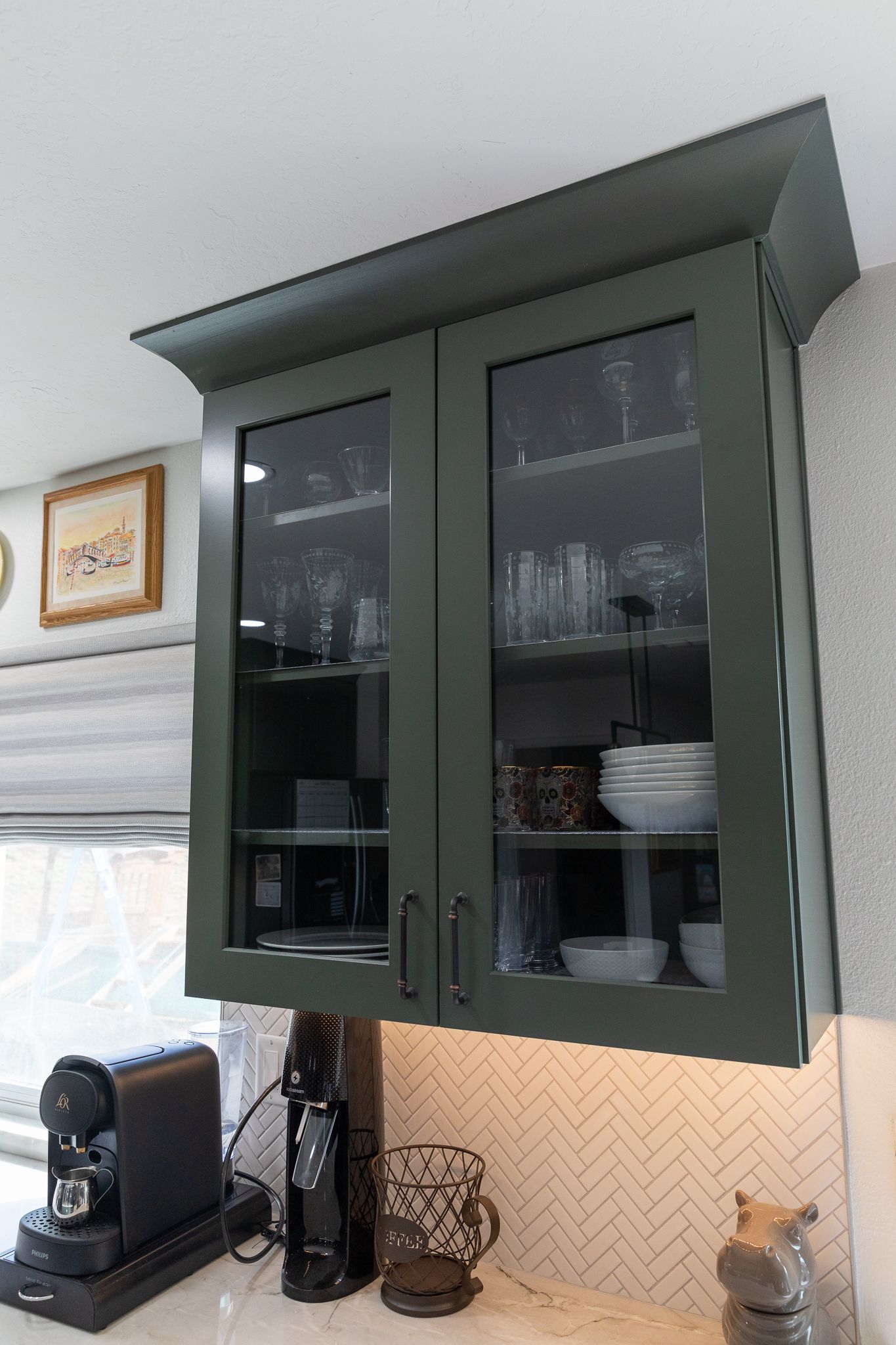 A kitchen with green cabinets and glass doors
