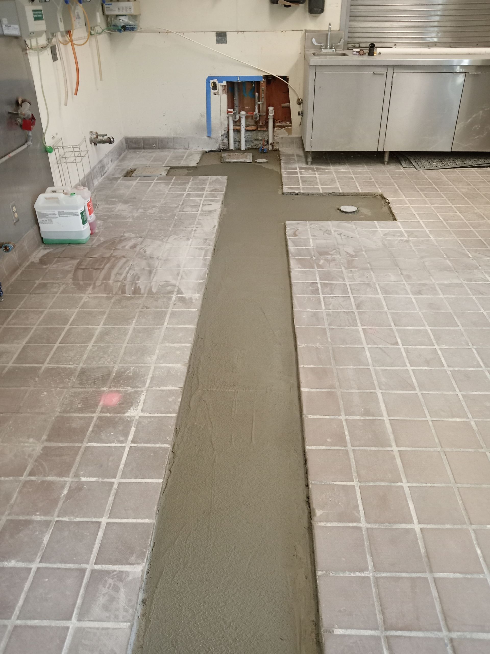 A kitchen with tile floors and concrete being poured on the floor