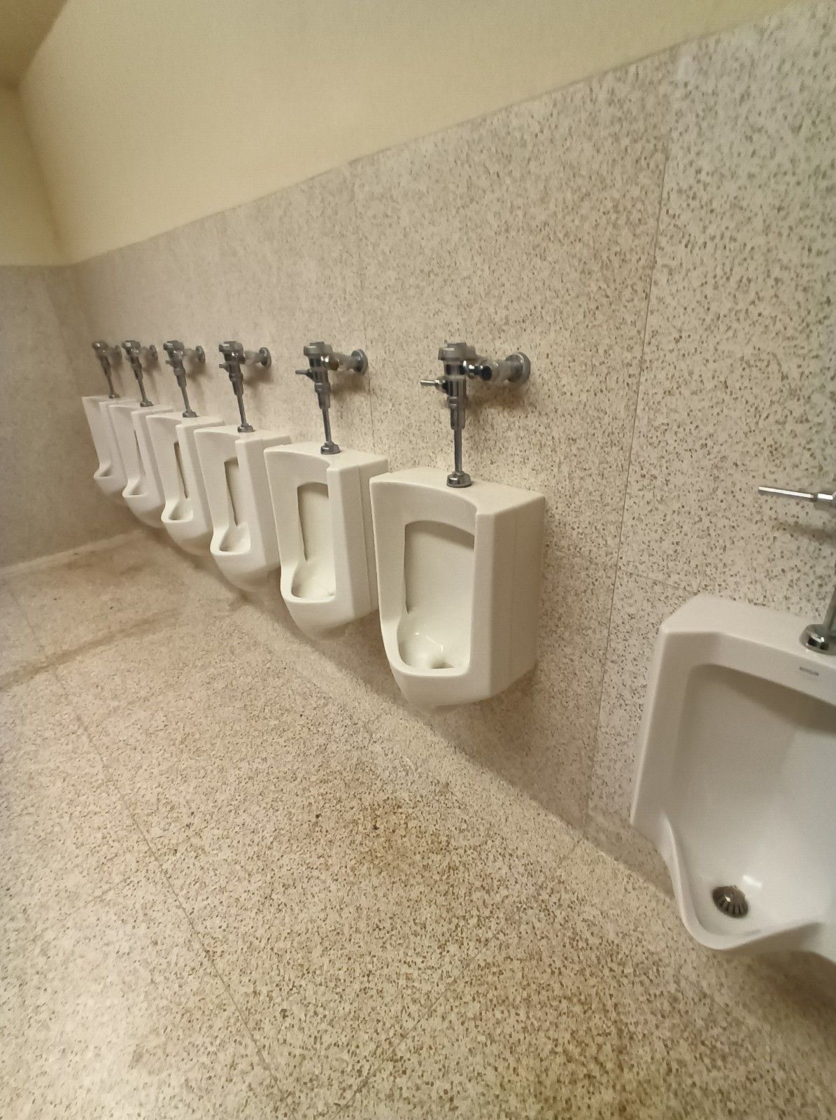 A row of urinals are lined up in a public restroom.