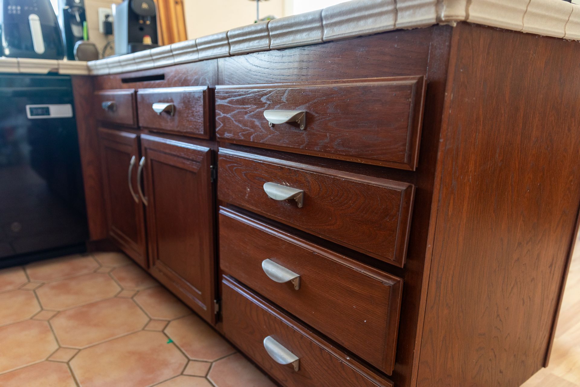 A kitchen with wooden cabinets and drawers and a black dishwasher