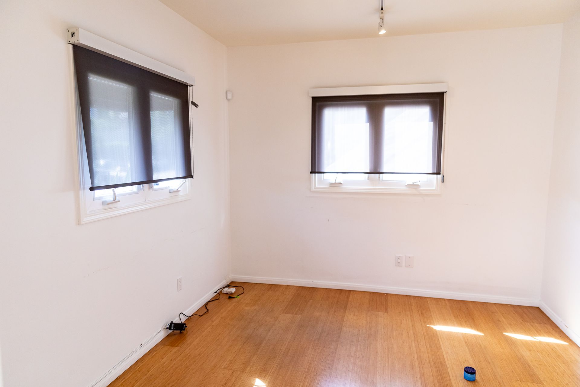 An empty room with hardwood floors and two windows.