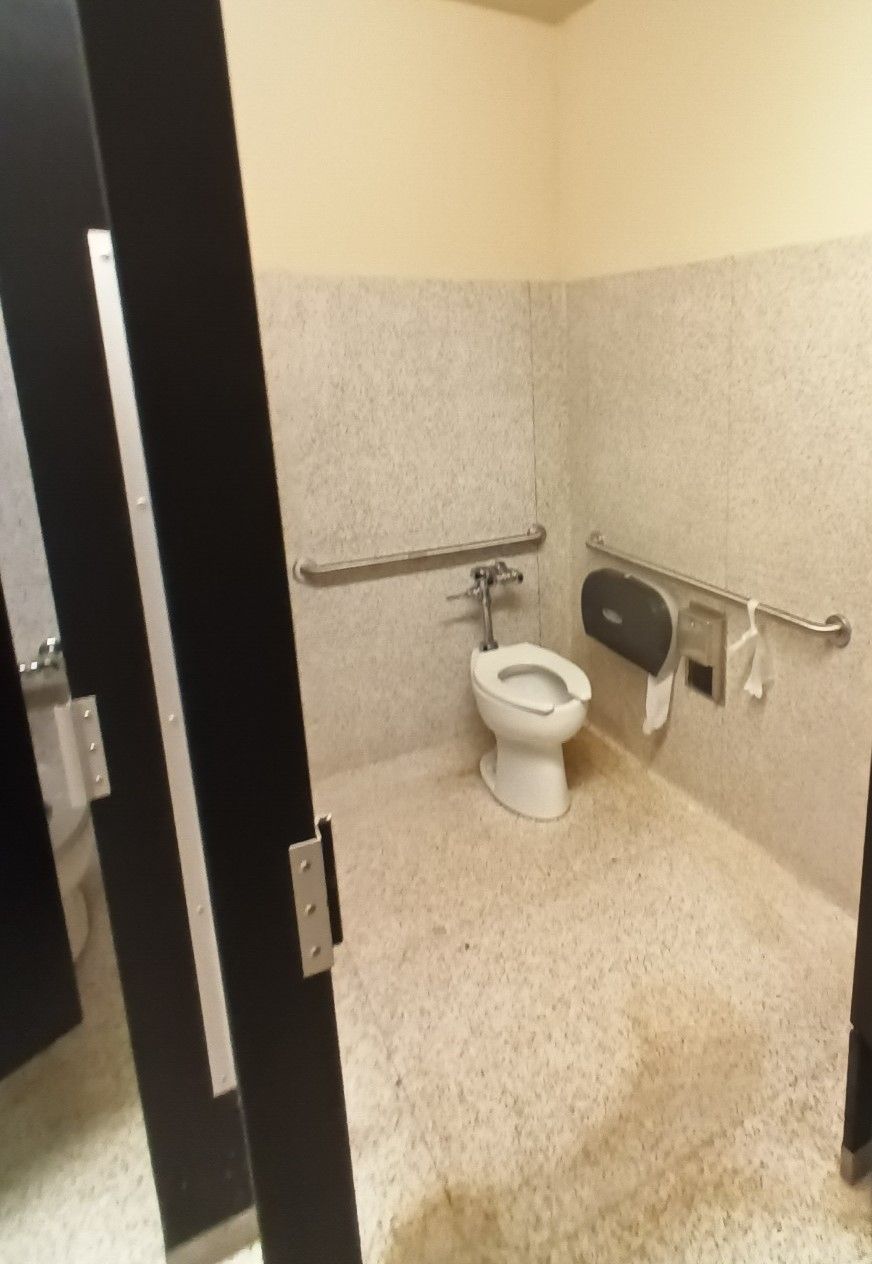 A bathroom with a toilet and a paper towel dispenser