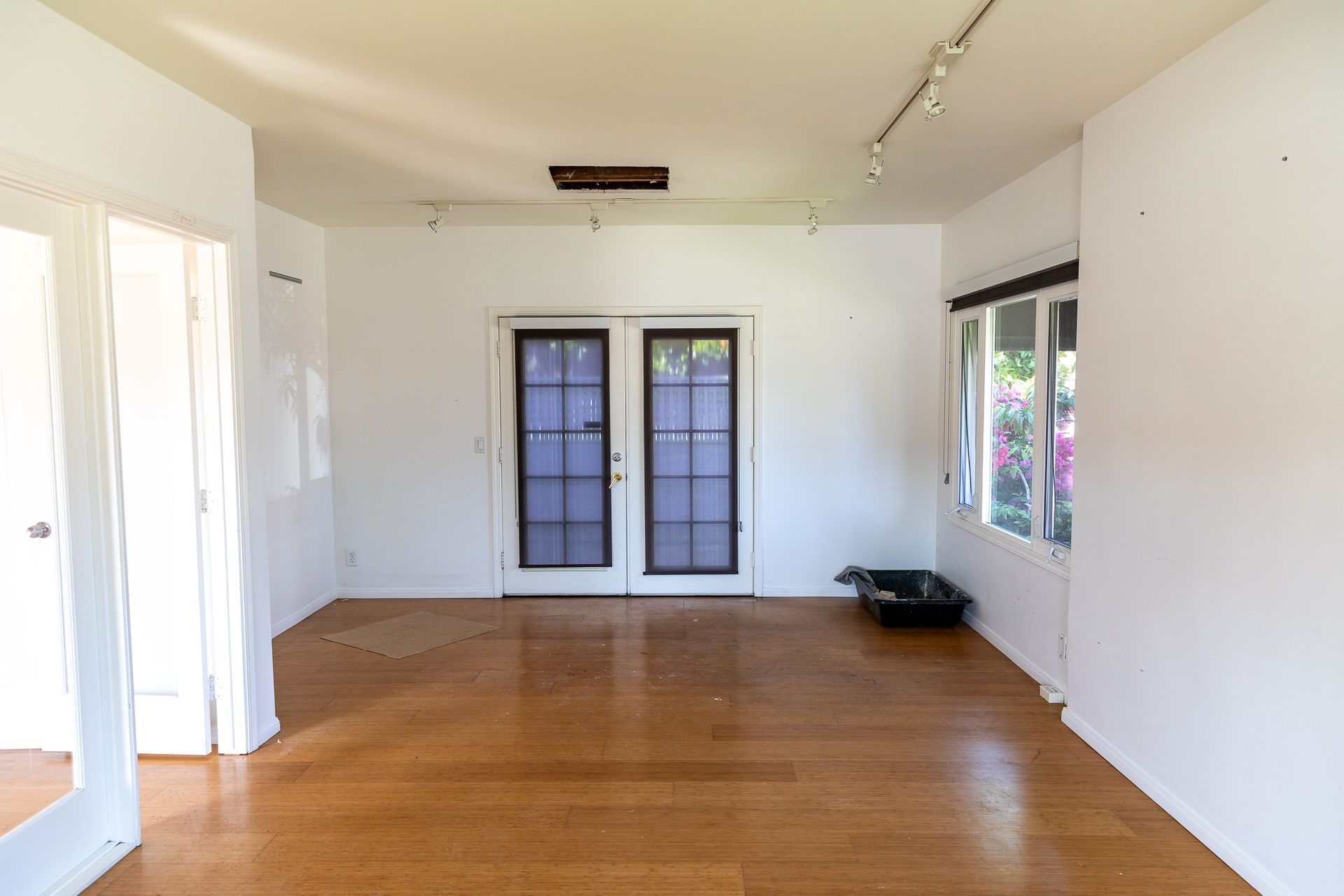 An empty living room with hardwood floors and white walls.